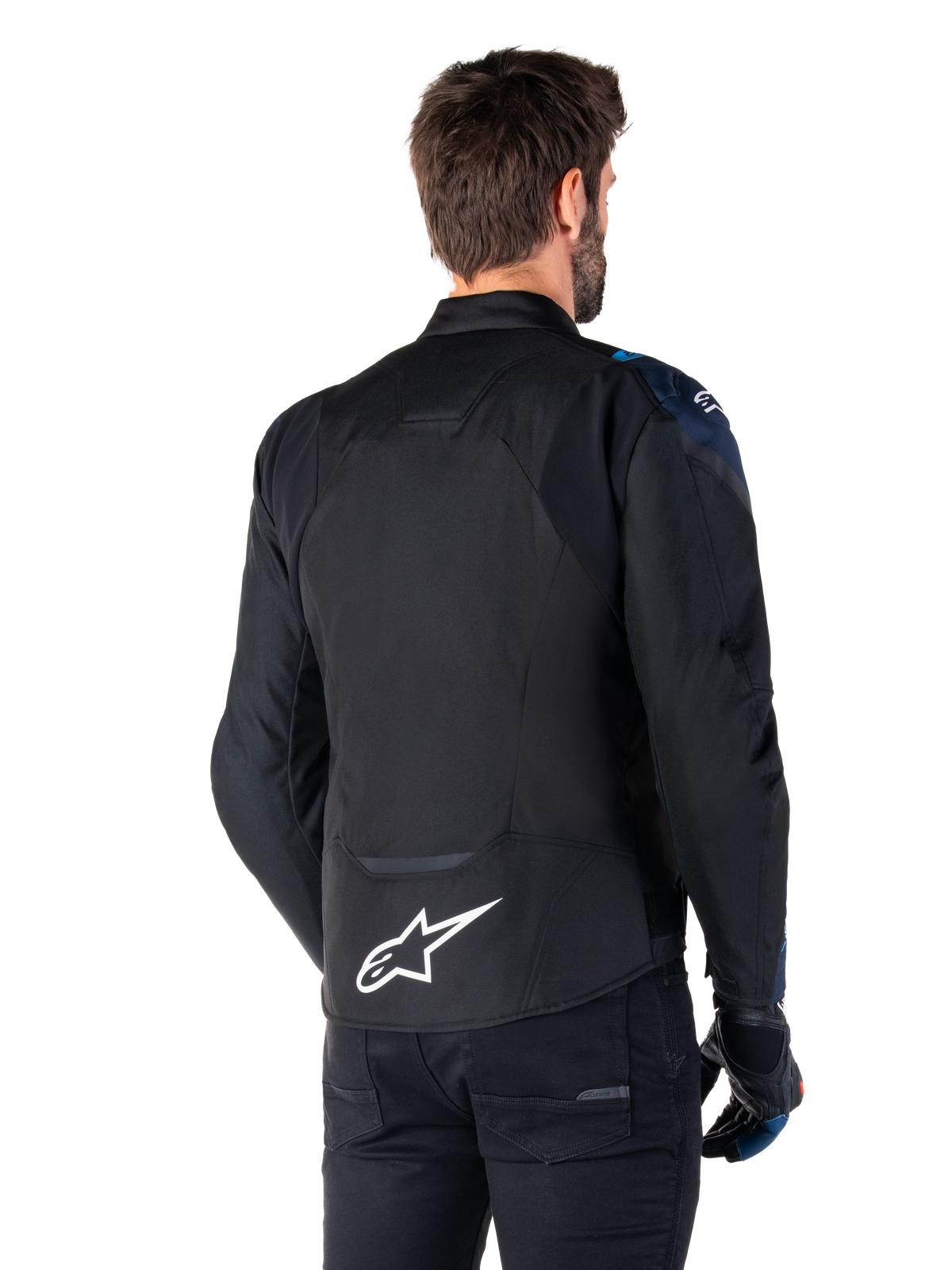 Veste imperméable Alpinestars T-Jaws V4, vue de dos, noir avec détails bleu foncé et bleu Blithe, logo étoile blanc sur le bas du dos, silhouette sport, portée avec un pantalon noir et des gants de moto