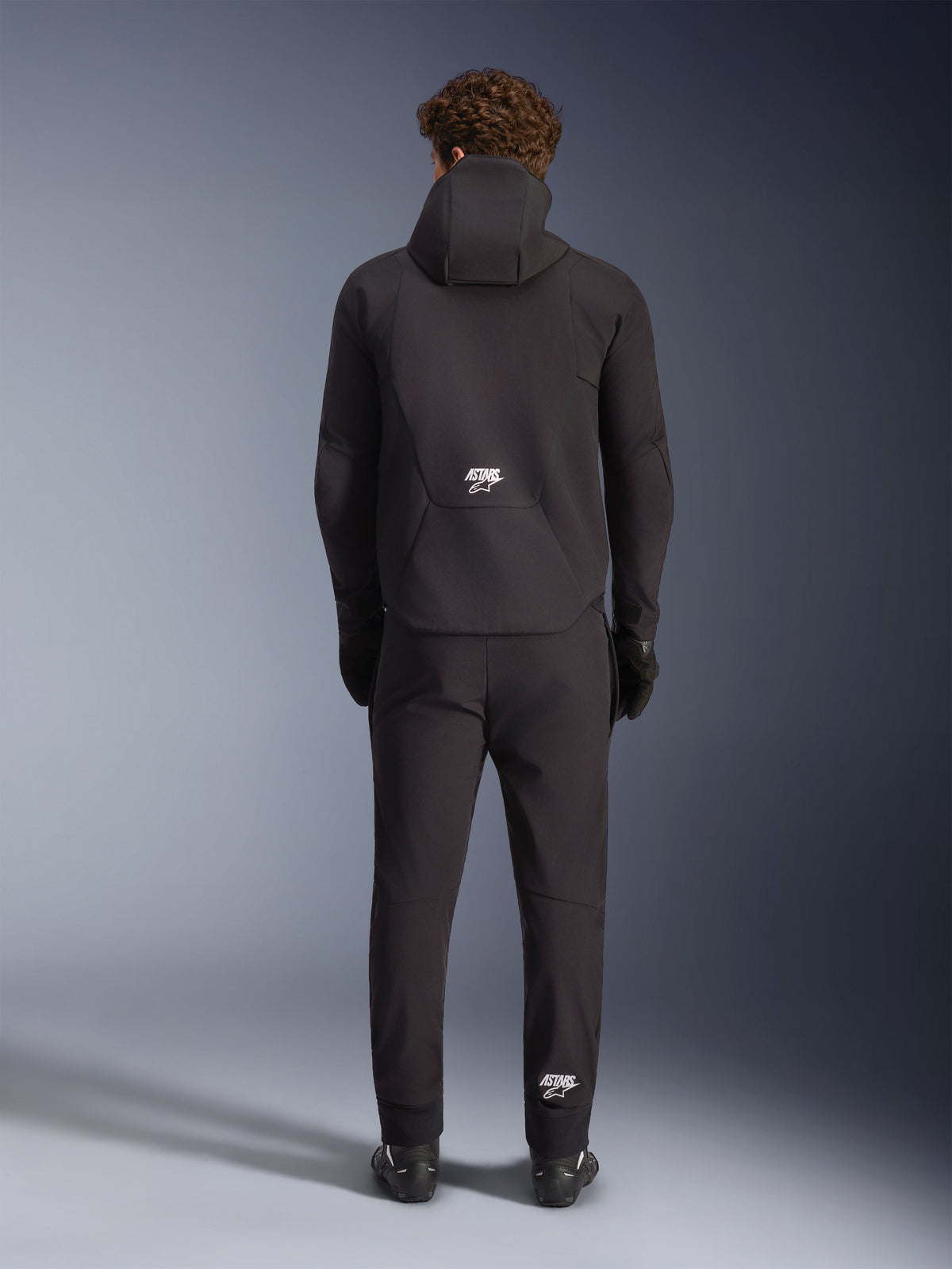 Alpinestars Aeroshell waterdichte jas, zwarte heren softshell motorjas met capuchon, achteraanzicht met wit ASTARS-logo