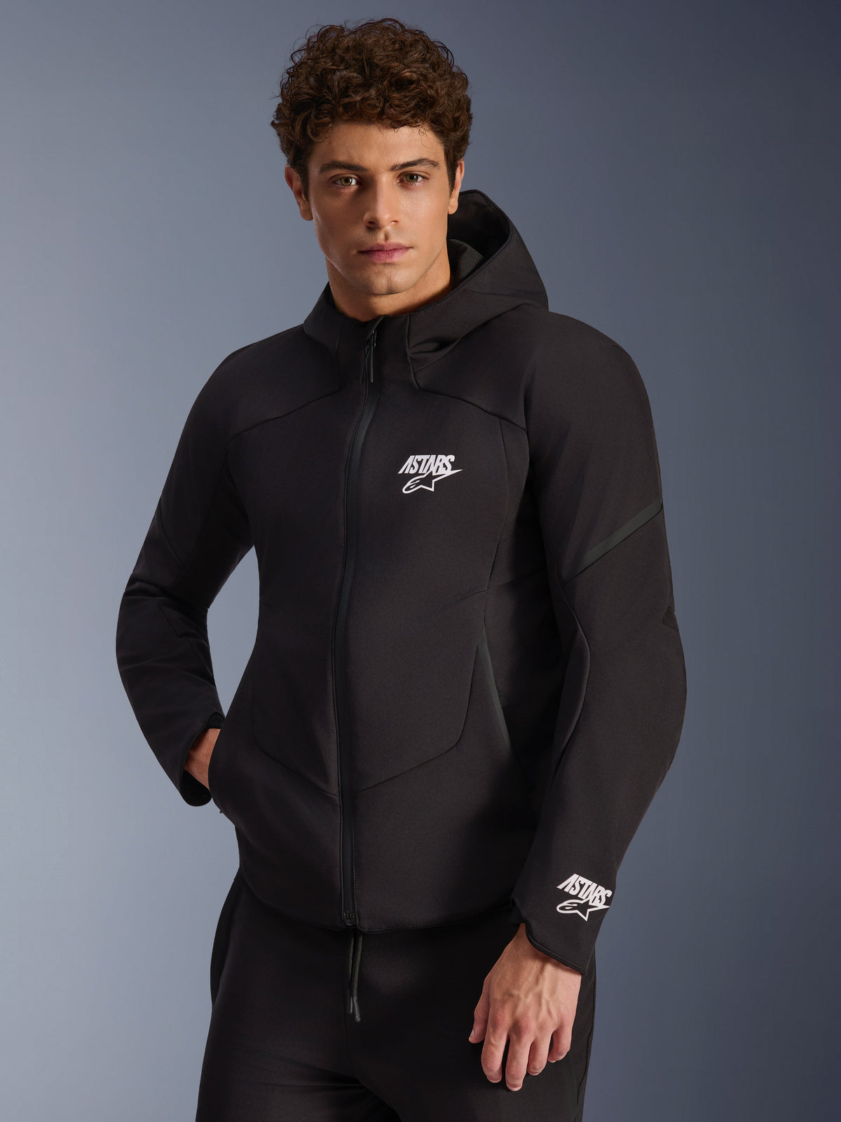 Alpinestars Aeroshell waterdichte jas, zwarte softshell herenmotorjas met witte ASTARS-logo's en geïntegreerde capuchon.