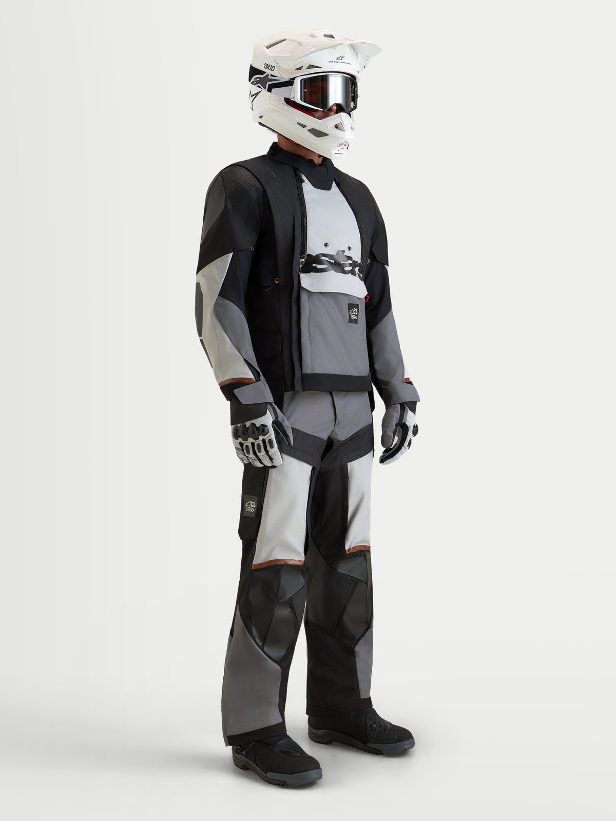 Alpinestars Harok V2 Drystar jas, heren adventure motorjas in donkergrijs, ijsgrijs en zwart, gedragen met bijpassende motoruitrusting, helm en handschoenen, voorzien van modulair ventilatiesysteem en waterdichte constructie