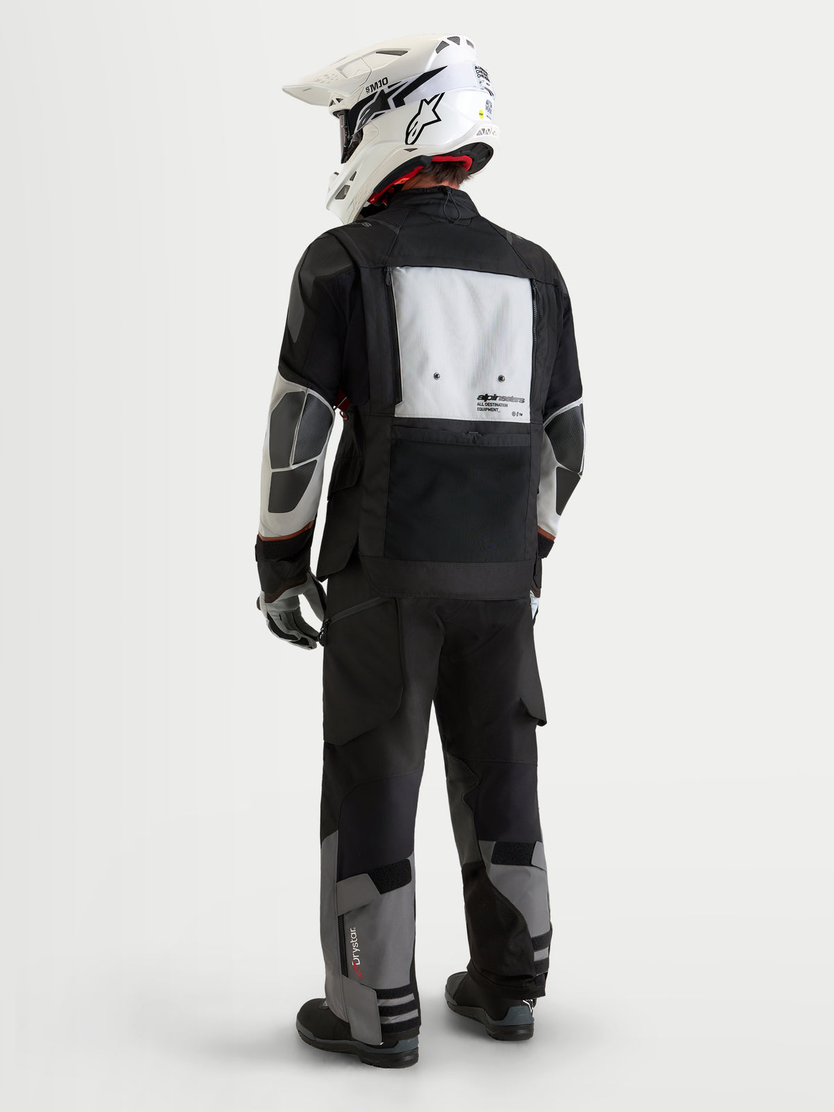 Alpinestars Harok V2 Drystar jas, heren adventure-motorjas, donkergrijs, ijsgrijs en zwart, achteraanzicht met modulair ventilatiepaneel, PU-verstevigingszones en bijpassende adventure-broek met een witte off-road helm