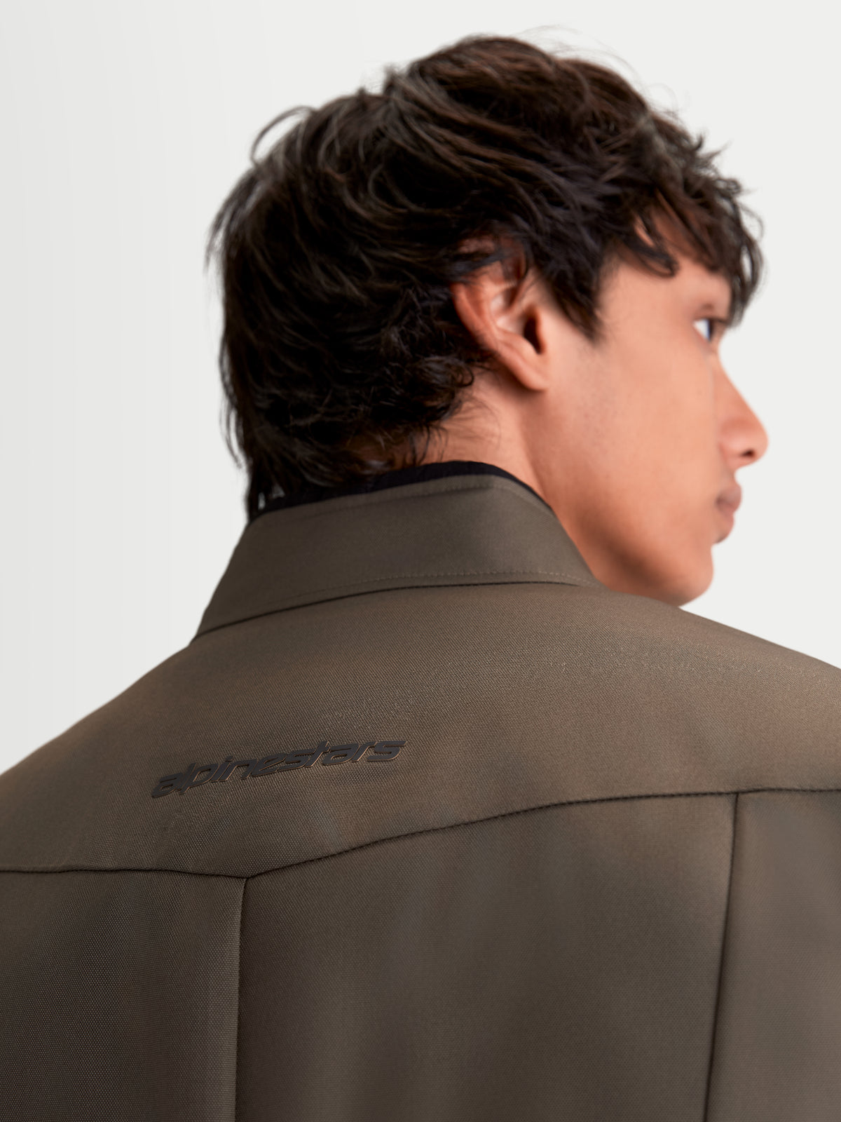 Alpinestars C-1 Waterproof Veste, veste de moto urbaine contemporaine textile pour homme en coloris marron et noir, vue rapprochée de dos montrant le col souple et le logo Alpinestars portée par un modèle