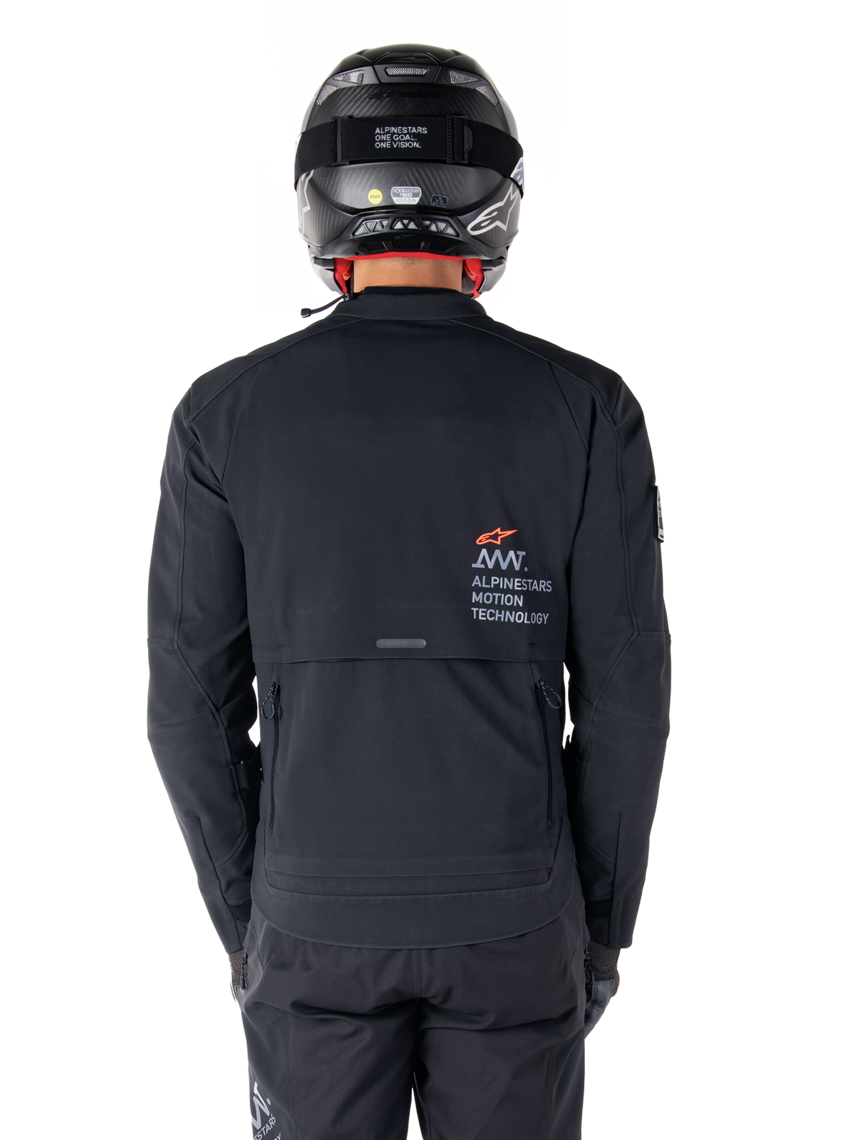 Alpinestars AMT-8 Stretch Drystar® XF Jacke, Rückansicht, Schwarz, getragen mit schwarzem Helm und Hose, mit Alpinestars Motion Technology Branding auf dem Rücken, Adventure-Touring-Design aus ergonomischem Stretchmaterial.