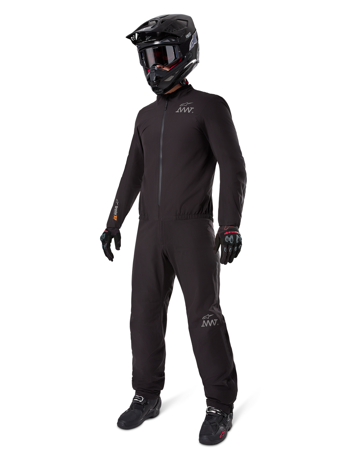 Alpinestars AMT-8 Stretch Drystar® XF Liner, schwarzer wasserdichter Motorradanzug, getragen mit schwarzem Helm, Schutzbrille und Handschuhen, mit AMT- und Drystar XF-Branding, funktionale Adventure-Ausrüstung für Allwetterschutz.