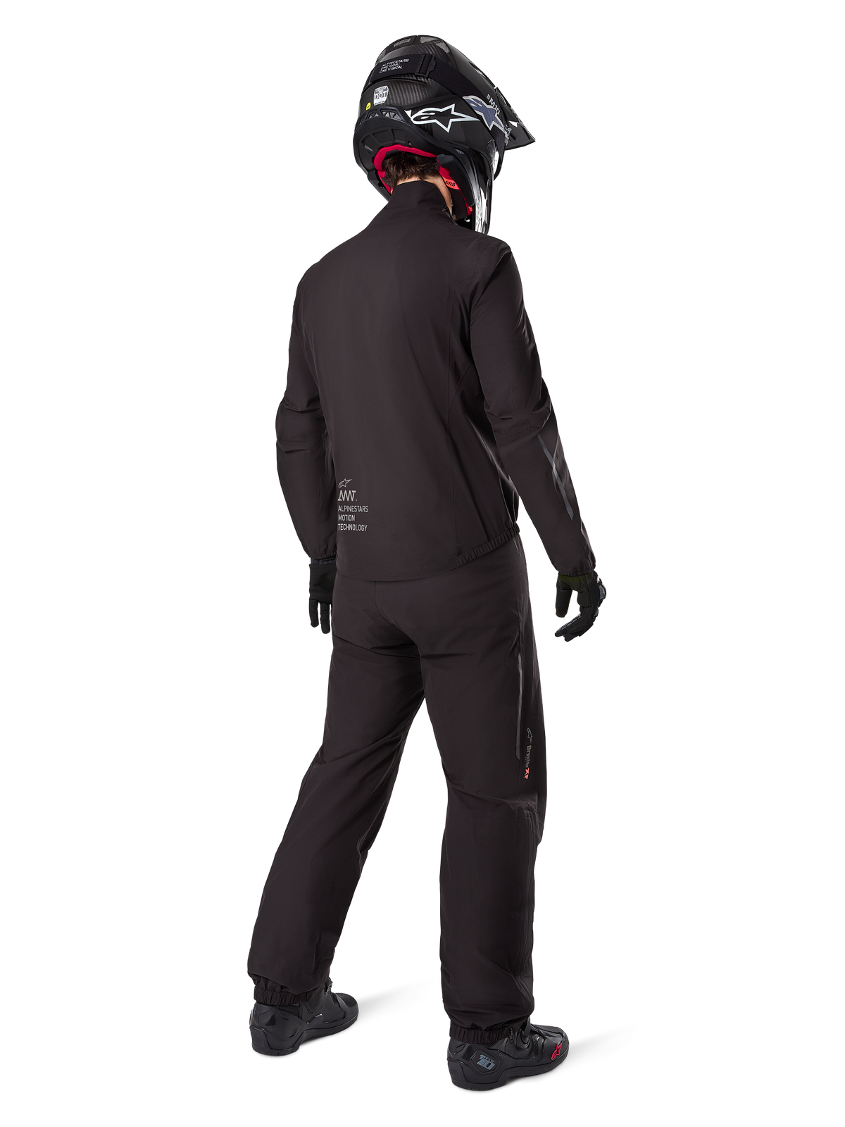 Rückansicht eines Fahrers mit dem Alpinestars AMT-8 Stretch Drystar® XF Jackenfutter, schwarze technische Motorradausrüstung, getragen mit passender Hose und schwarzem Helm, mit „AMT Alpinestars Motion Technology“-Branding auf dem Rücken, schlichtes minimalistisches Design für Adventure-Touren