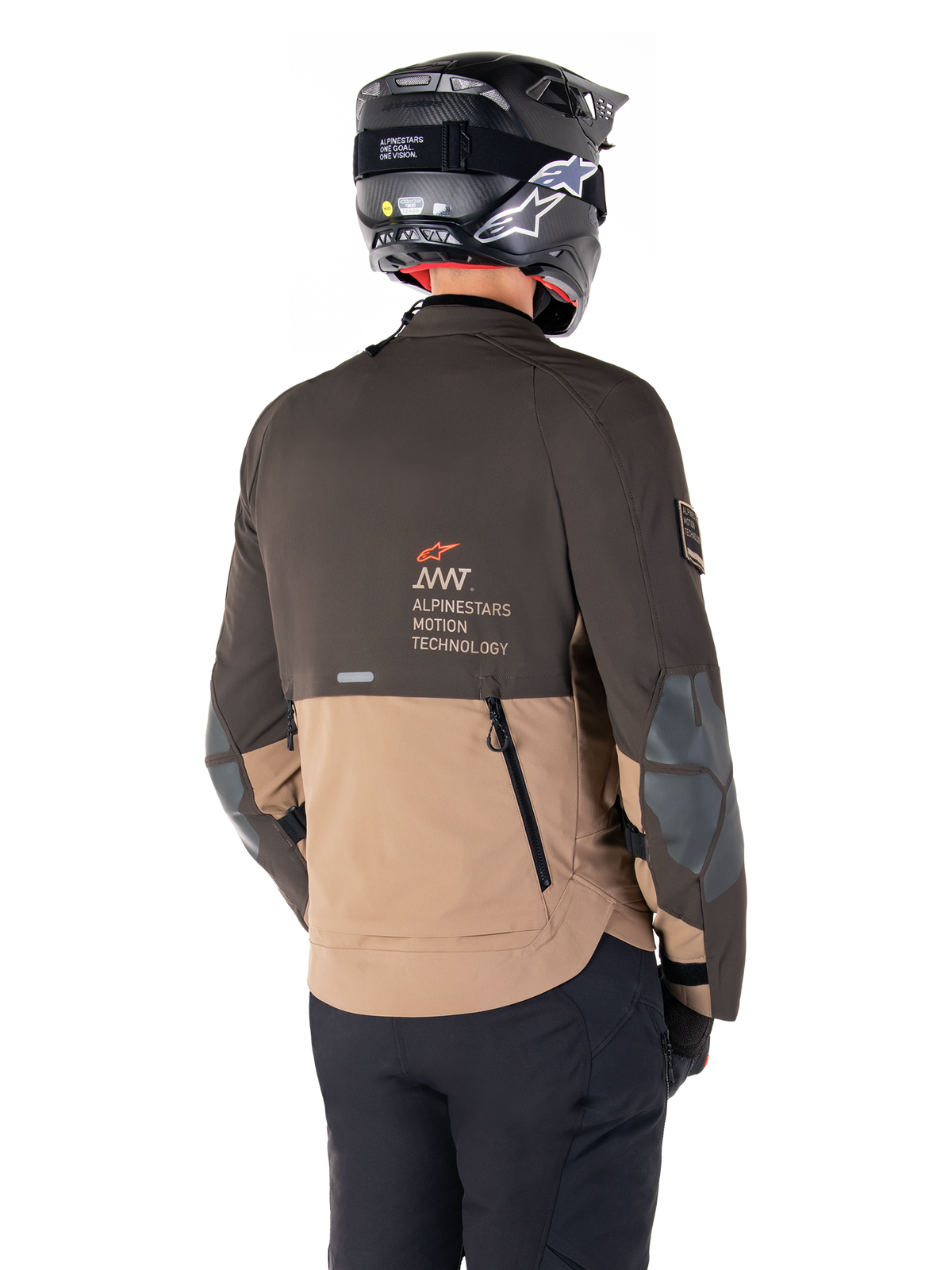 Alpinestars AMT-8 Stretch Drystar® XF Jas, adventure motorjas, donkerbruin en donkerkhaki, achteraanzicht met AMT Alpinestars Motion Technology branding, tweekleurig textielontwerp met ventilatieritsen op de rug en dakpanontwerp, gedragen met zwarte helm en motorbroek