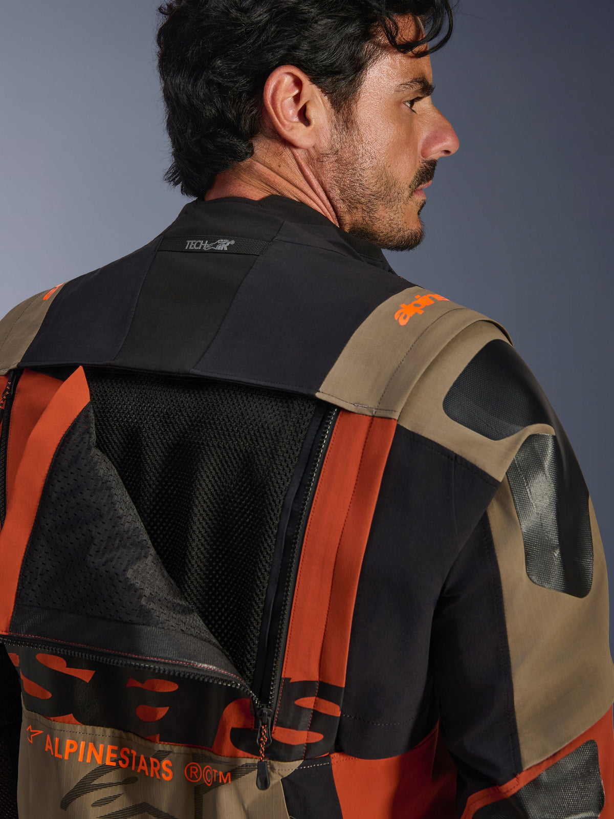 Alpinestars Halo Pro Drystar® XF Laminierte Jacke in Walnut Rust Black, Nahaufnahme der Rückansicht, geöffnetes Belüftungspanel mit sichtbarem Mesh-Gewebe, Tech-Air® Branding am Kragen, strapazierfähige mehrfarbige Textilkonstruktion.