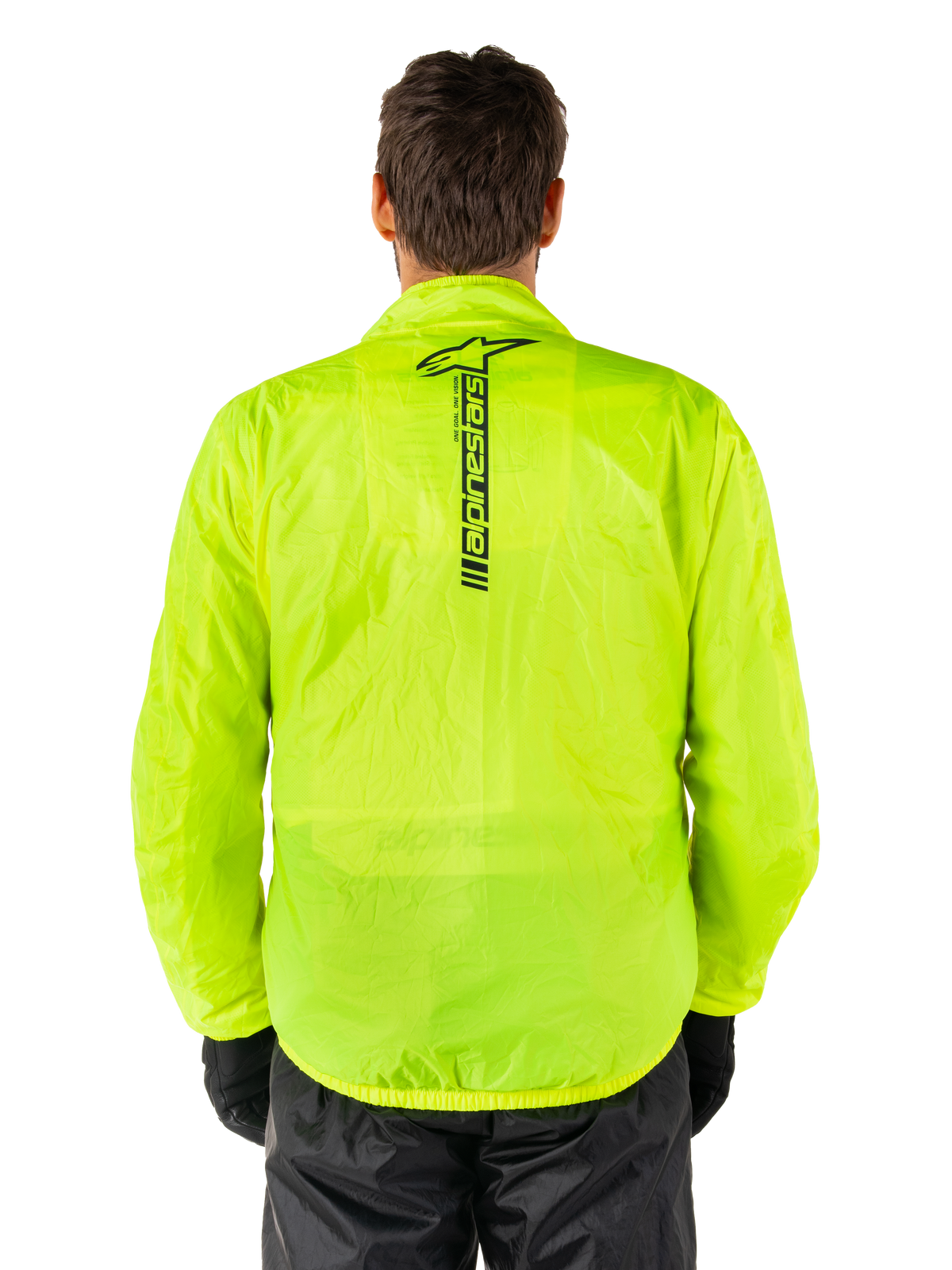 Alpinestars Hurricane Rain V2 Jacke, Motorrad-Regenjacke, Gelb Fluo, Rückansicht mit vertikalem schwarzem Alpinestars-Logo in der Rückenmitte, leichtes wasserdichtes Material, getragen mit schwarzer Fahrhose und Handschuhen