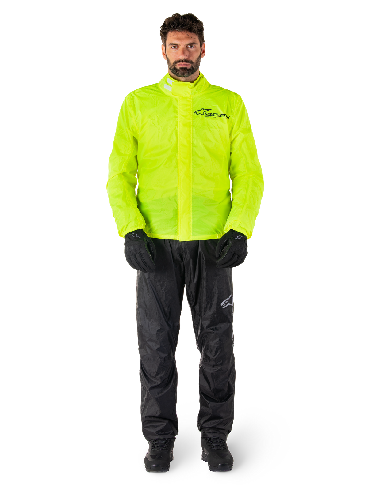 Alpinestars Hurricane Rain V2 jas en broek, neongeel en zwart, waterdicht motorregenpak gedragen met zwarte handschoenen en laarzen, voorzien van het Alpinestars-logo op de borst en het been