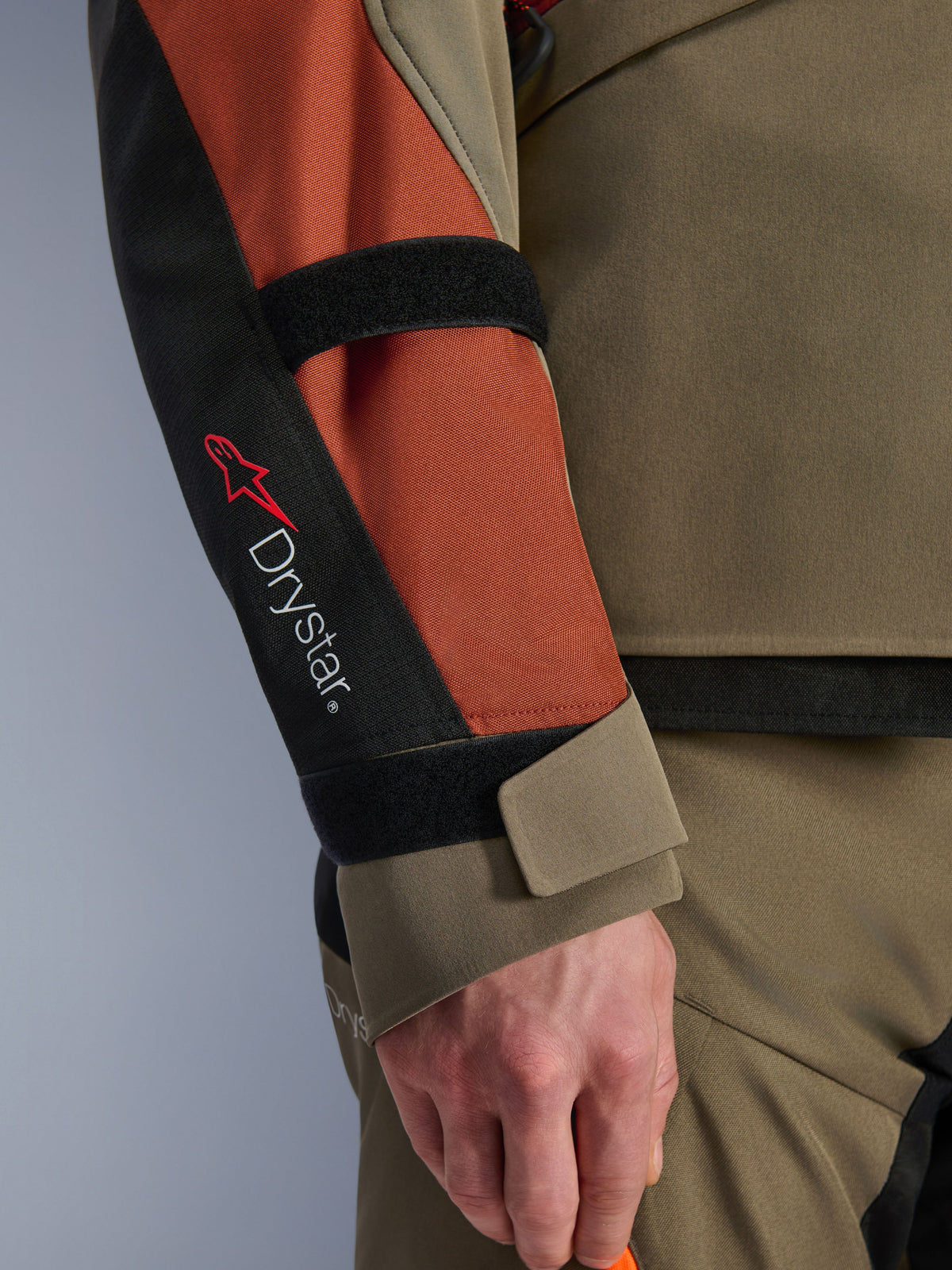 Alpinestars Andes V4 Drystar® Jacke, Motorradjacke, Walnut Rust Black, Nahaufnahme des Ärmels mit Drystar®-Branding und rotem Stern-Logo, verstellbare Klettverschlussriemen an Unterarm und Handgelenk, strapazierfähiges Adventure-Touring-Textildesign