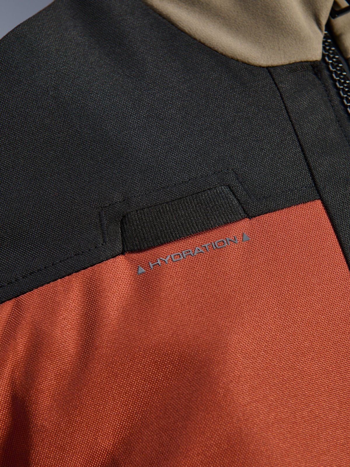 Alpinestars Andes V4 Drystar® Jacke, Detailansicht in Walnut Rust Black, integrierte Schlaufe für den Trinkschlauch auf der Brust, strapazierfähige Ripstop-Textilkonstruktion.