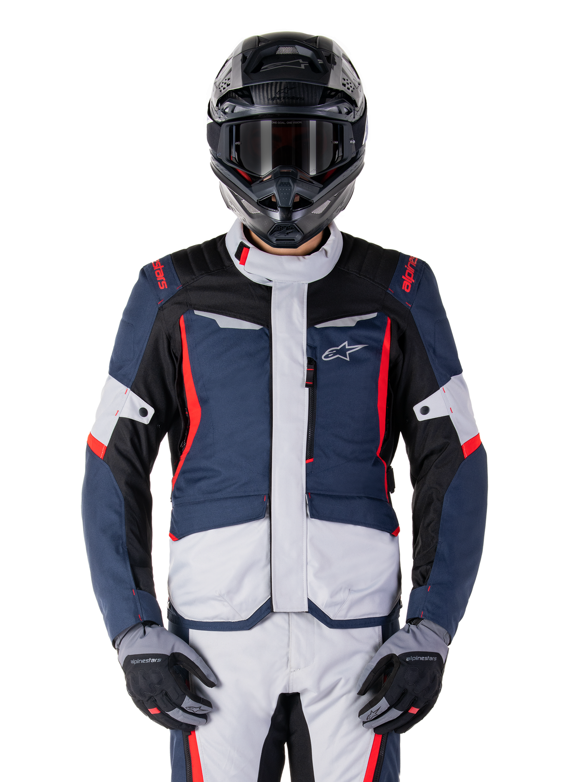 Veste imperméable Alpinestars ST-1, veste de tourisme d'aventure, bleu foncé, noir et rouge vif, portée avec un casque d'aventure noir et des gants gris, avec empiècements gris clair et accents rouges sur les épaules et les fermetures éclair, design épuré avec logo Alpinestars sur la poitrine, équipement de moto imperméable durable