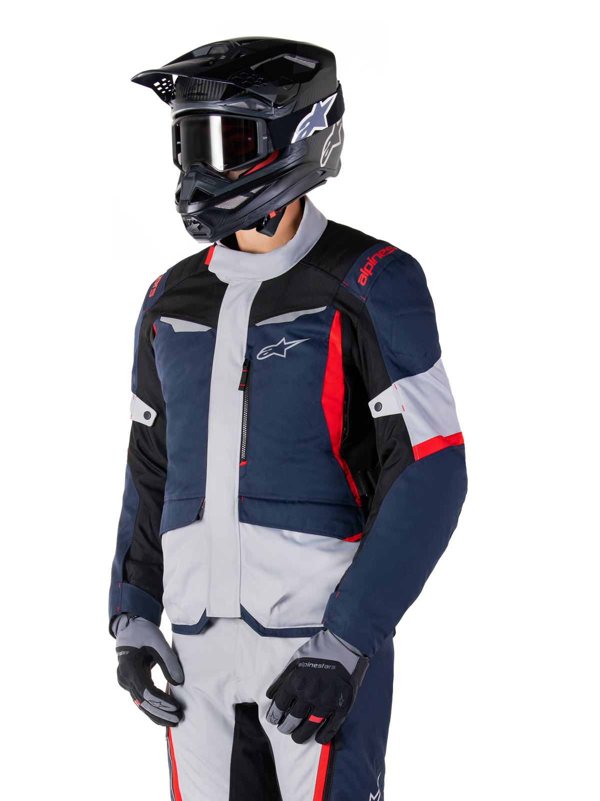 Veste Alpinestars ST-1 Waterproof, veste de moto d'aventure touring en bleu foncé, noir et rouge vif, portée avec un casque noir et des gants gris, dotée d'un design moderne avec des poches fonctionnelles et le logo Alpinestars.