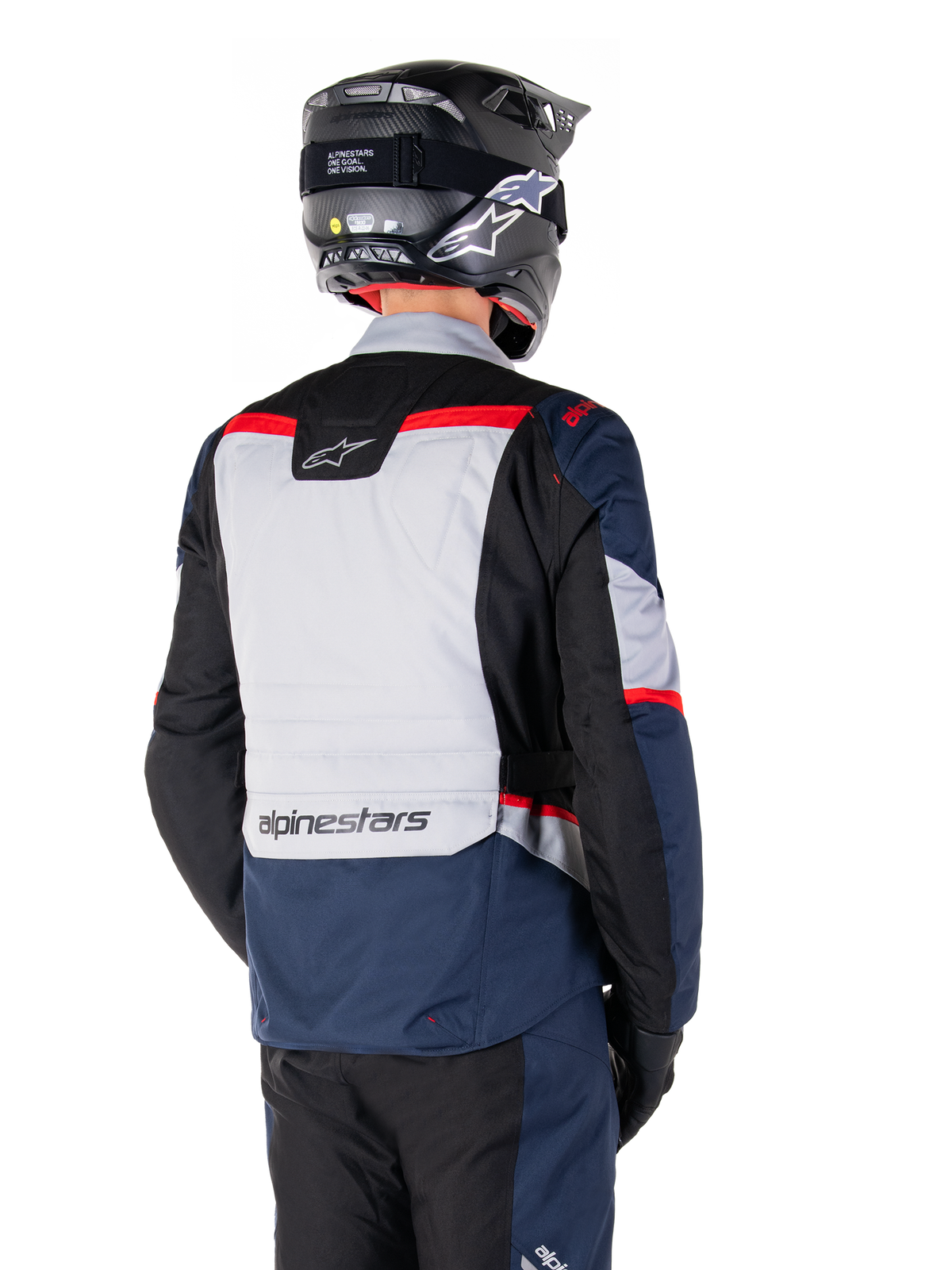 Veste imperméable Alpinestars ST-1, bleu foncé, noir et rouge vif, vue arrière d'un pilote portant un casque d'aventure noir, avec des panneaux gris clair et le marquage Alpinestars, équipement de moto adventure touring