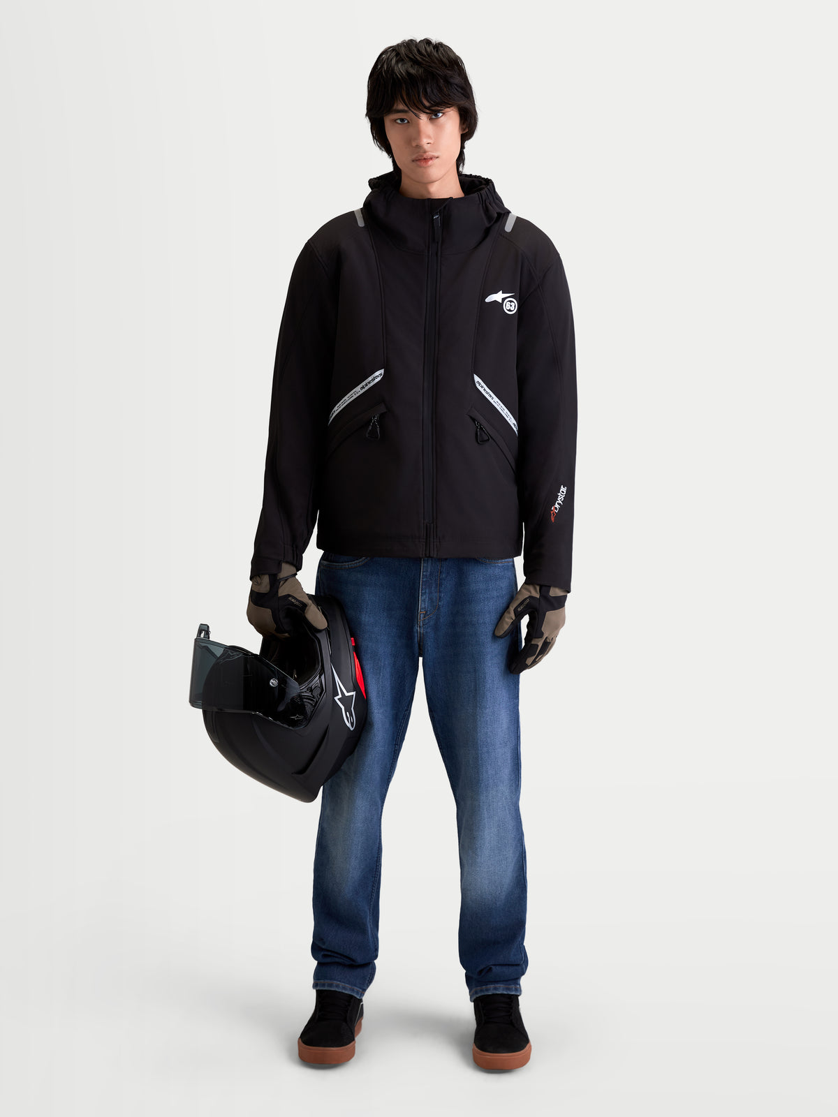 Alpinestars C-5 Drystar Jacket, men's urban contemporary motorcycle textile jacket in black, front view on a model wearing jeans, gloves, and holding a helmet, showcasing waterproof softshell construction and integrated hood.