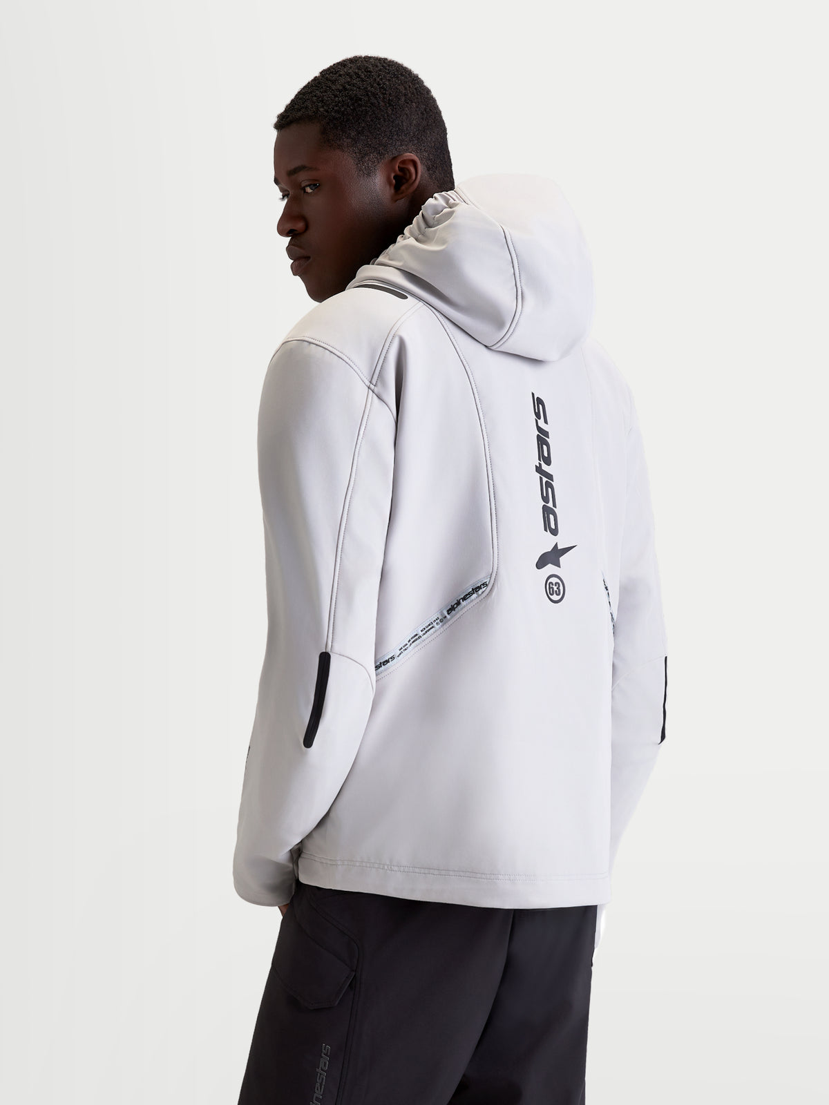 Alpinestars C-5 Drystar jas, heren urban motorjas in lichtgrijs en zwart, achteraanzicht op model met geïntegreerde capuchon, softshell constructie en verticaal logo op de rug