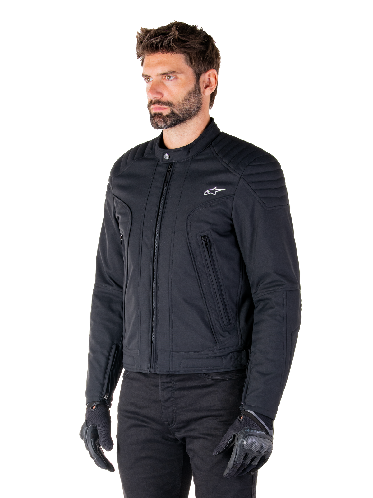 Veste Alpinestars Clayton WR, noire, veste de moto urbaine en textile avec détails matelassés sur les épaules et les avant-bras, coupe ajustée, finition mate, portée par un pilote avec des gants noirs.