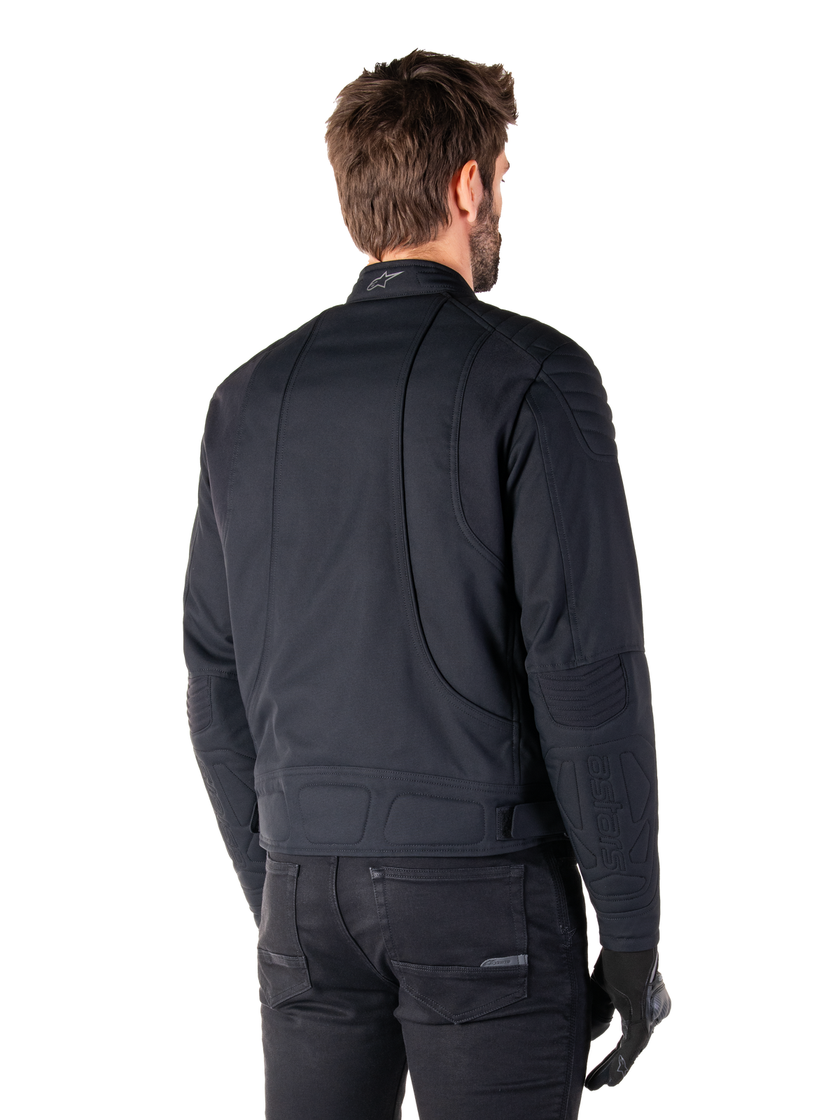 Veste Alpinestars Clayton WR en noir, vue de trois-quarts arrière sur un mannequin, veste de moto urbaine avec rembourrage matelassé aux épaules et aux coudes, lignes de couture techniques et logo réfléchissant sur le col, portée avec un pantalon et des gants noirs.