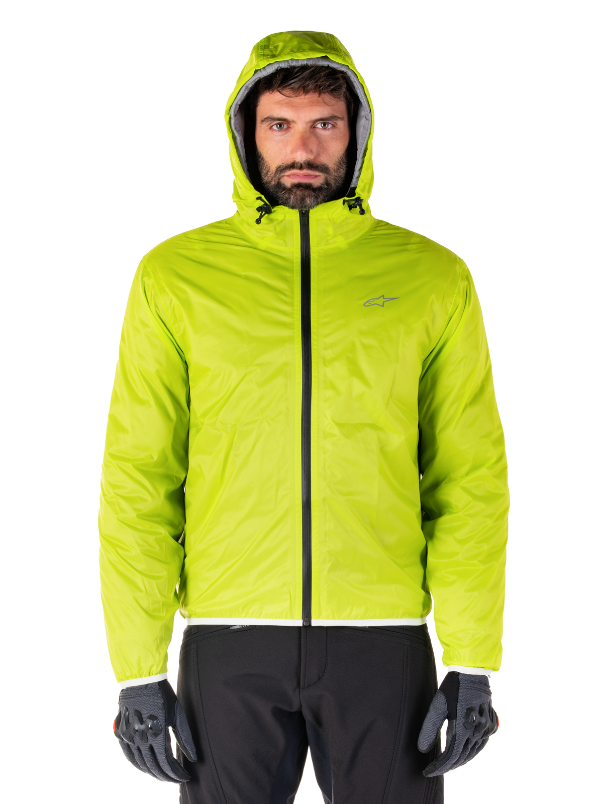 Alpinestars Mohobbs Waterproof Jacket, Lime Punch opvouwbare regenhoes, fel limoengroene shell met capuchon gedragen met zwarte motorbroek en grijze motorhandschoenen, urban moto-streetwear stijl.