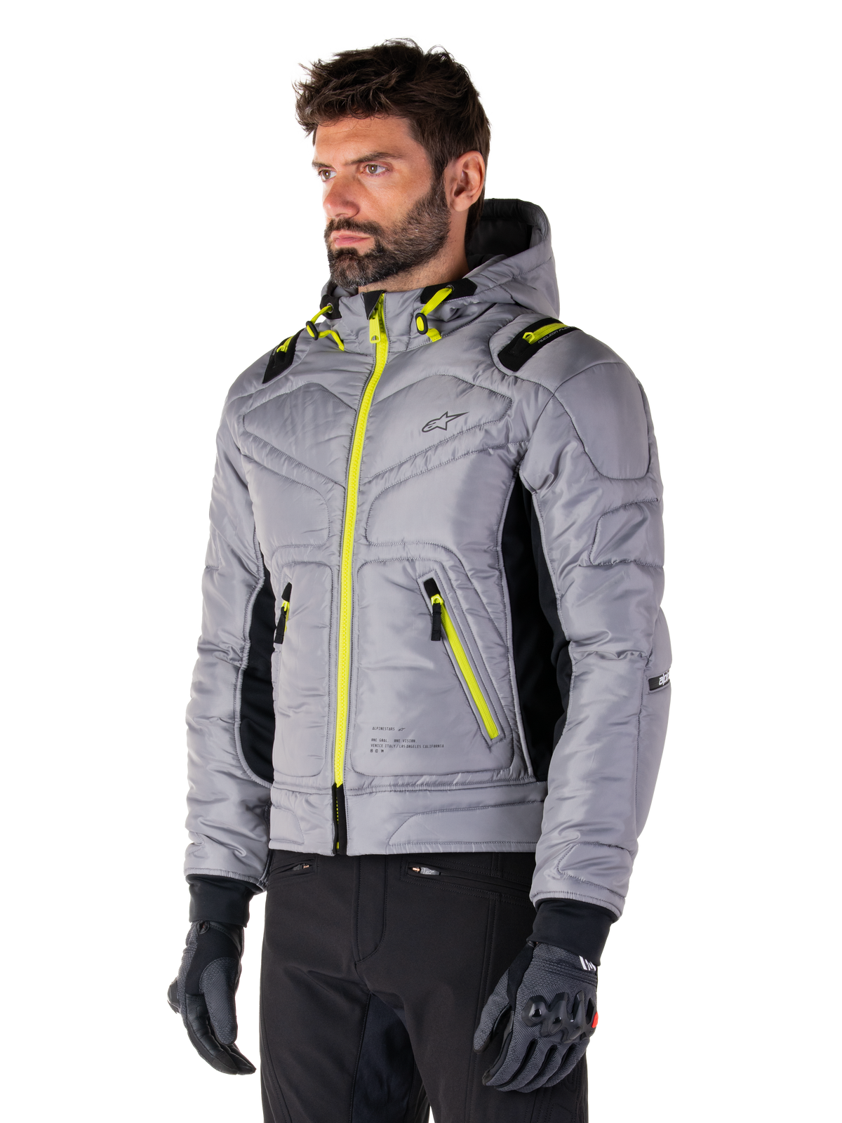 Alpinestars Mohobbs Waterproof Jacket, Lunar Gray Lime Punch, gewatteerd bomberjack voor heren met neongele ritsen en trekkoordaccenten, gedragen met zwarte motorbroek en handschoenen, modern urban moto streetwear-ontwerp met een capuchon