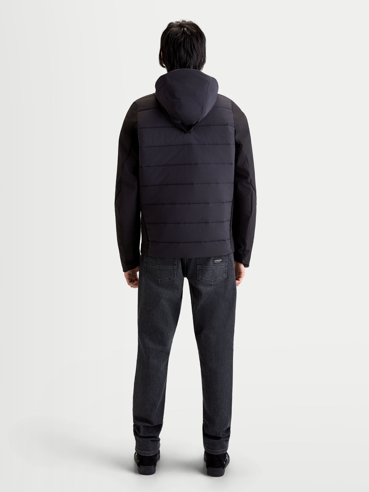 Alpinestars Therma Tech WP Veste, veste de moto urbaine pour homme noire, vue de dos sur un modèle portant le système de capuche intégré et la construction matelassée thermosoudée