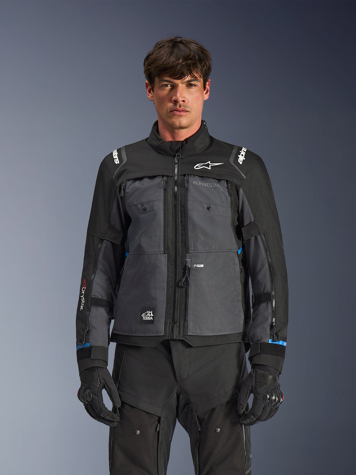Alpinestars Cusco Drystar® Jacket, Motorcycle Touring Jacket, Black and Deep Gray, front view on model, featuring Alpinestars logos on chest and shoulders, Drystar® sleeve branding, technical multi-pocket design with ventilation zippers, paired with black riding gear