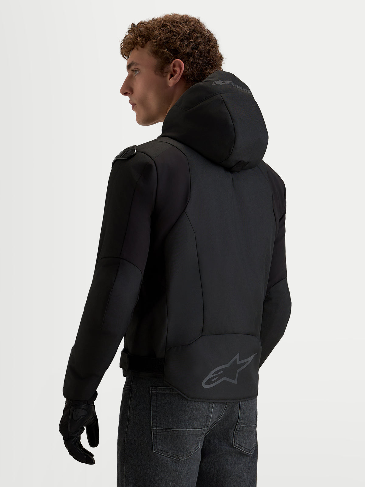 Veste de moto Alpinestars Zaca V2 Waterproof, veste étanche pour homme noire avec capuche intégrée et logo Alpinestars à l'arrière, vue de profil.