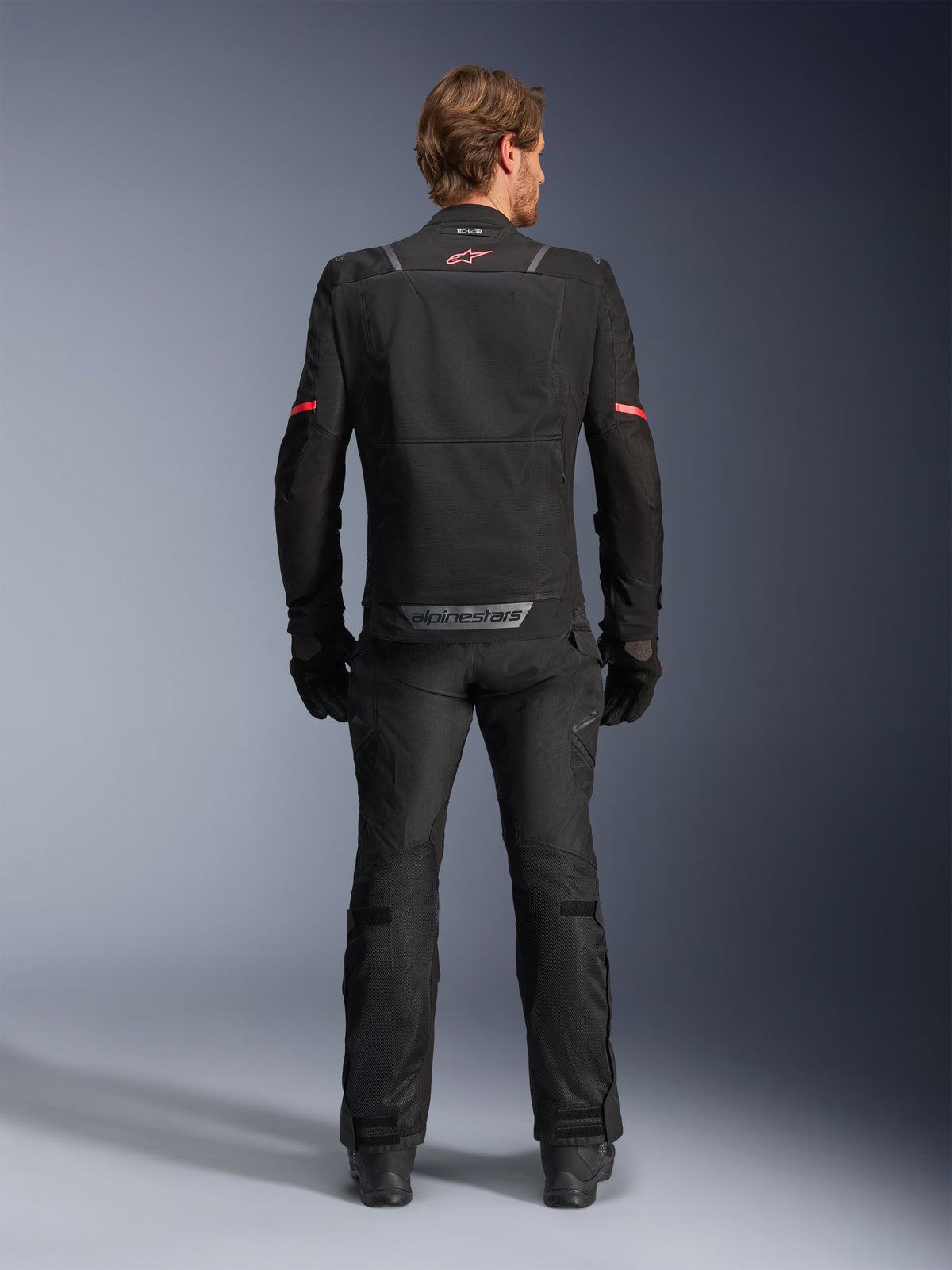 Alpinestars ST-2 Air jas, zwarte heren motortouringjas met mesh ventilatie op de rug, achteraanzicht van model in zwarte outfit.