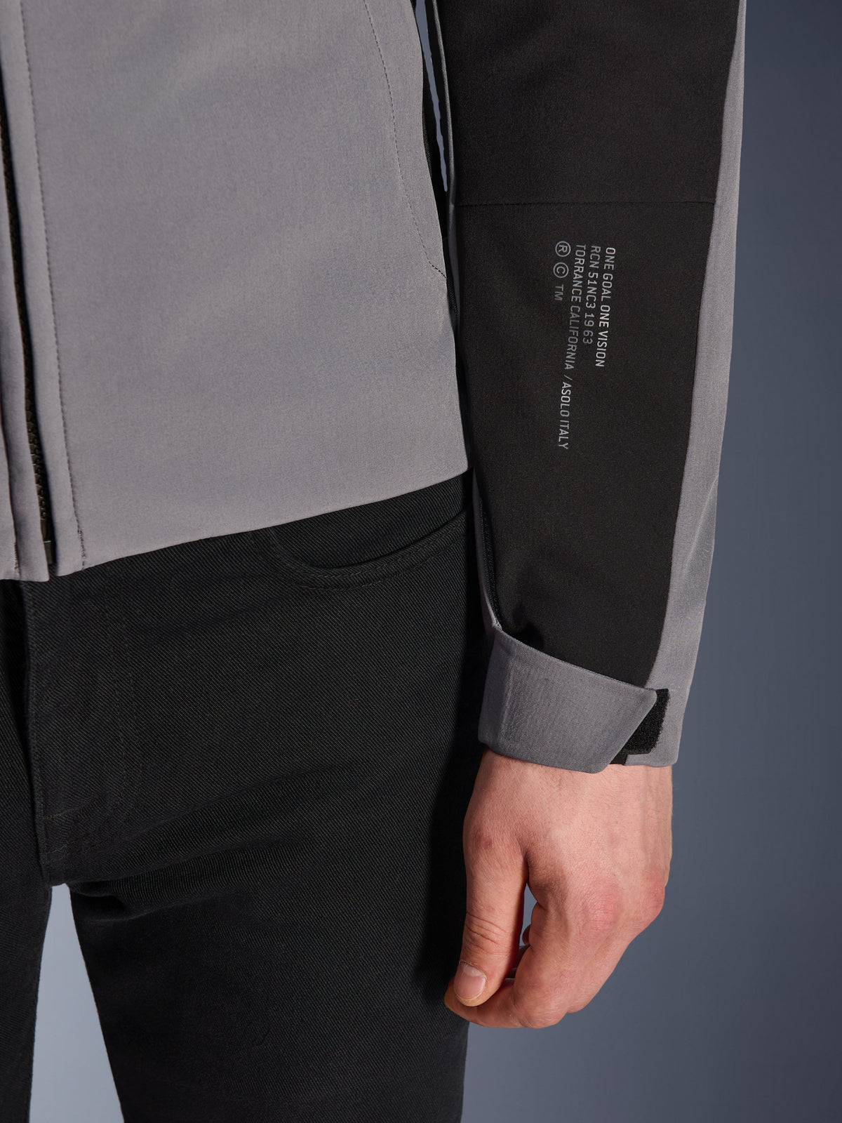 Alpinestars SMX Waterproof Jacket, donkergrijs en zwart, close-up van de mouw met wit gedrukte tekst met merkdetails, verstelbare klittenbandmanchet, sportief textielontwerp voor motorrijden onder alle weersomstandigheden