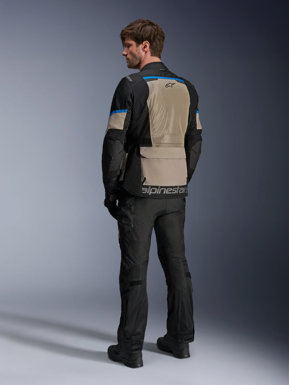 Alpinestars Andes Air Drystar® Jas, Black Laurel Gray en Bright Blue, achteraanzicht met groot mesh ventilatiepaneel op de rug, logo op de onderste zoom, gedragen met zwarte motorbroek en laarzen