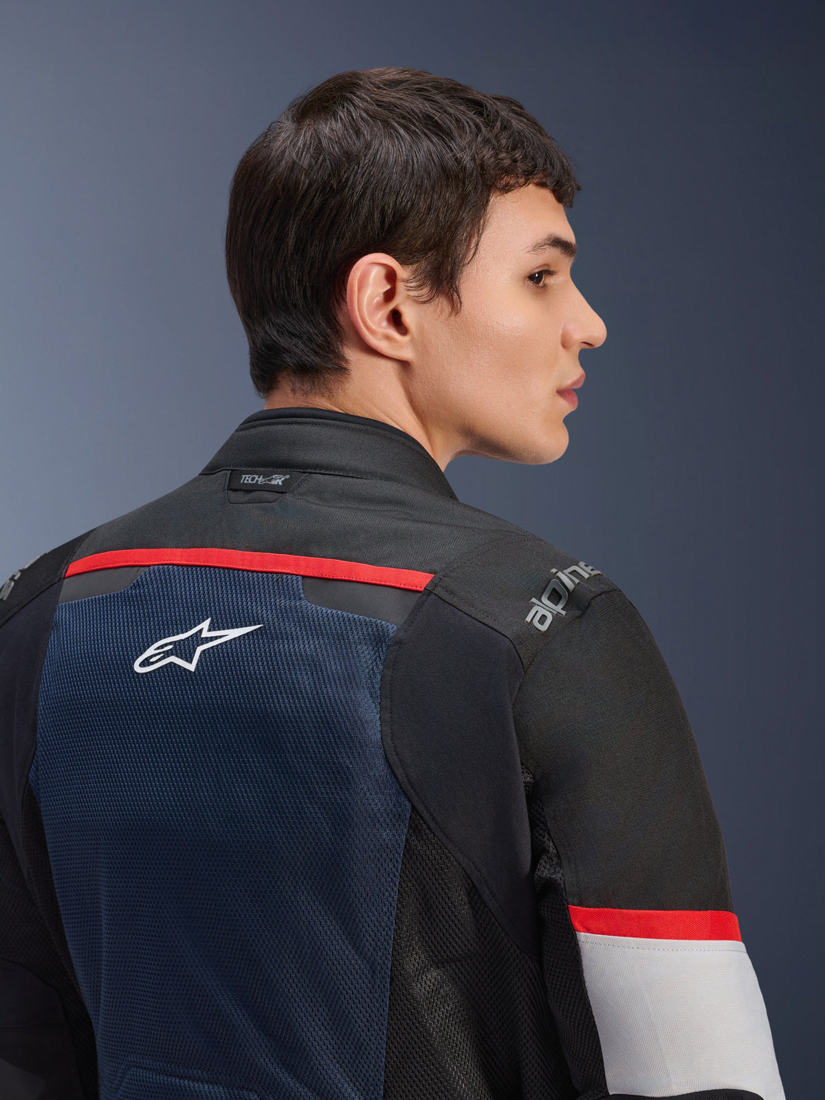 Alpinestars Andes Air Drystar® Jas, Deep Blue Black en Ice Gray, close-up achteraanzicht op een model, ademend mesh-paneel met wit ster-logo, rode accenten en Tech-Air®-branding op de kraag, touring motorjas voor twee seizoenen
