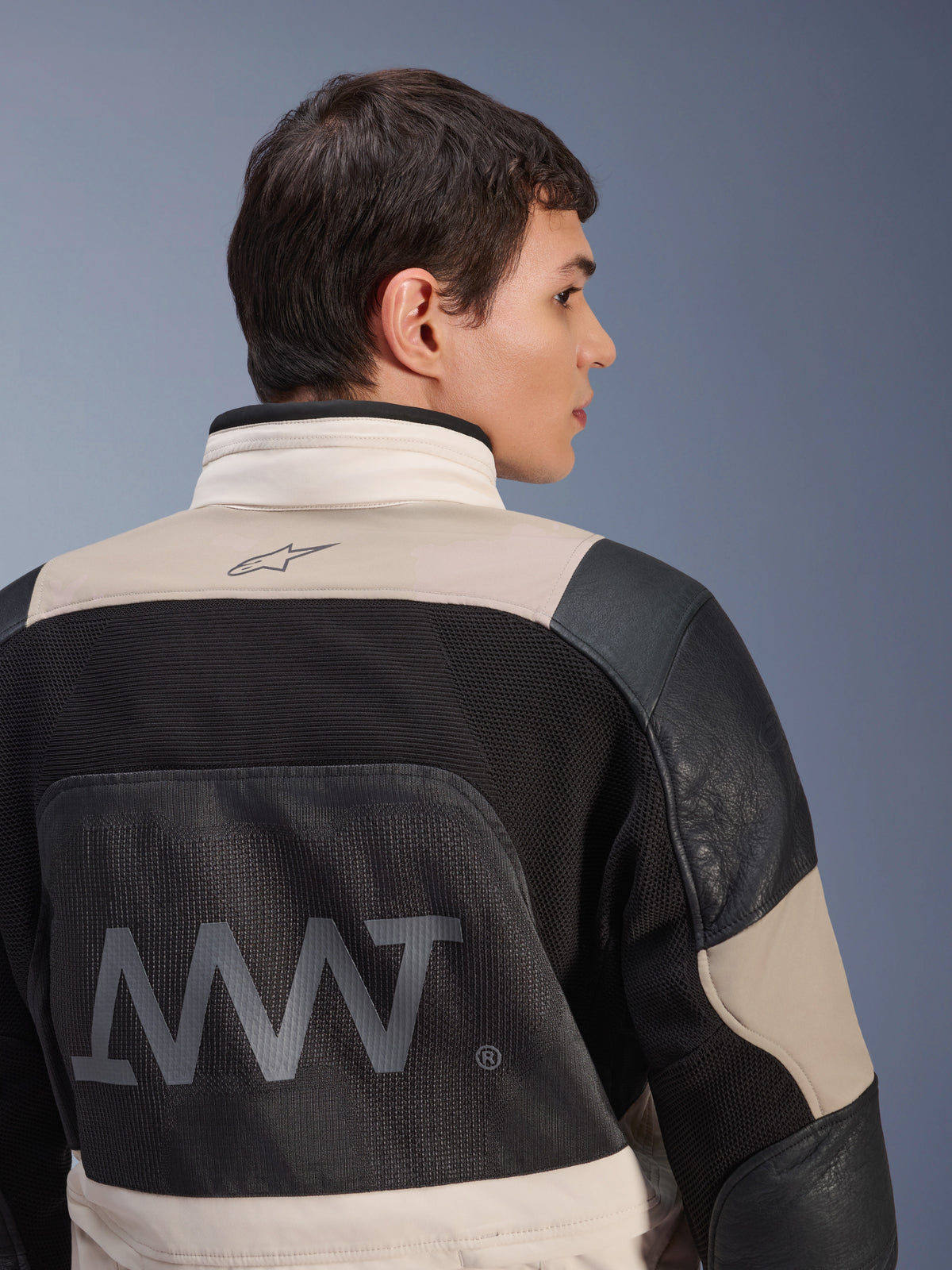 Alpinestars AMT-10LAB Drystar® XF Jacke, Rückansicht an männlichem Model, White Sand Aluminum Camo und Schwarz, mit großem AMT-Branding, Mesh-Belüftungseinsätzen und Lederverstärkungen, technische Adventure-Motorradbekleidung