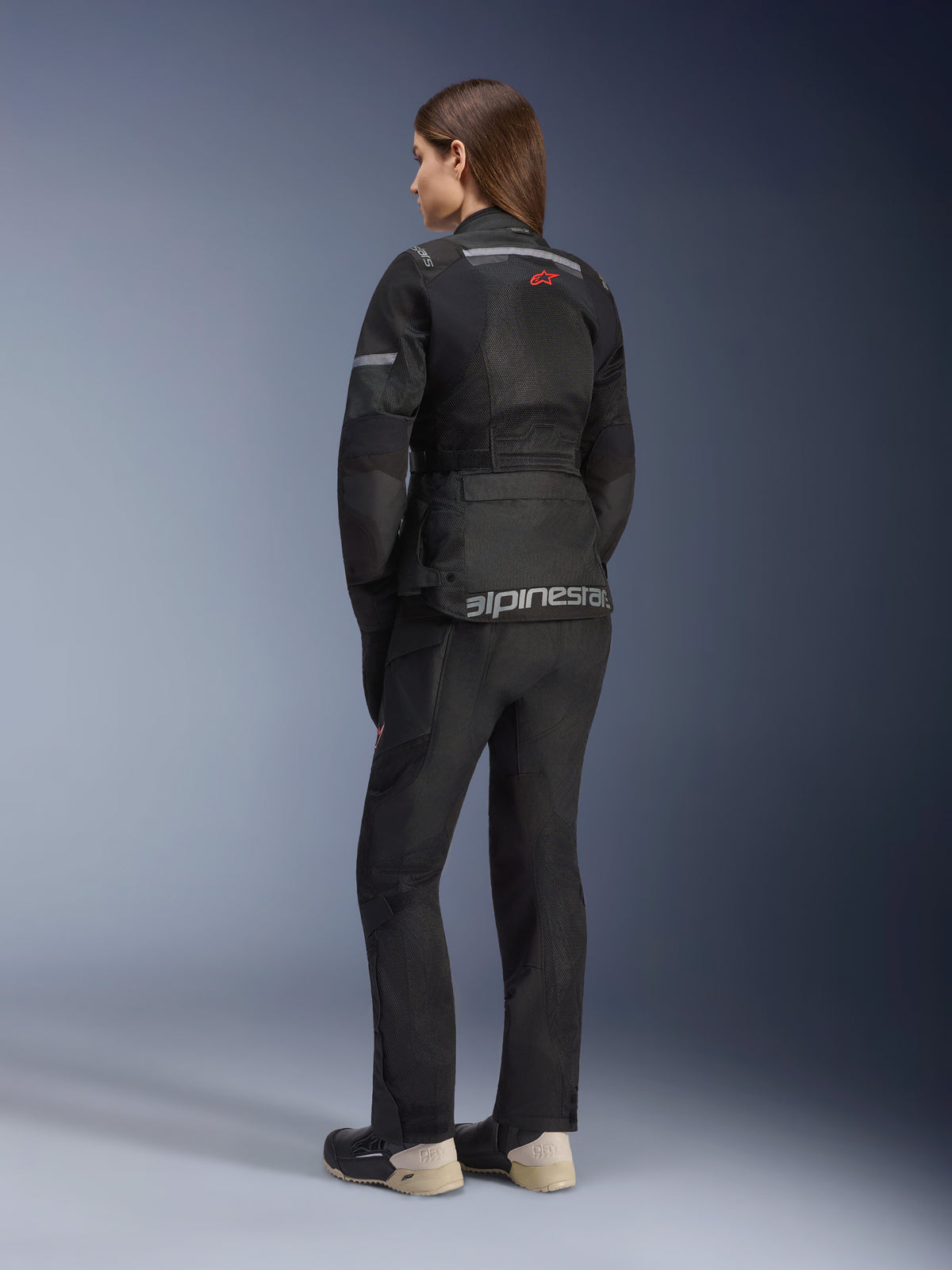 Alpinestars Stella Andes Air Drystar® Jacket, veste de touring moto pour femme, noire, vue de dos portée avec un pantalon et des bottes assortis, dotée de larges panneaux de ventilation en maille, d'un logo étoile rouge et d'un marquage Alpinestars argenté sur le bas du dos.