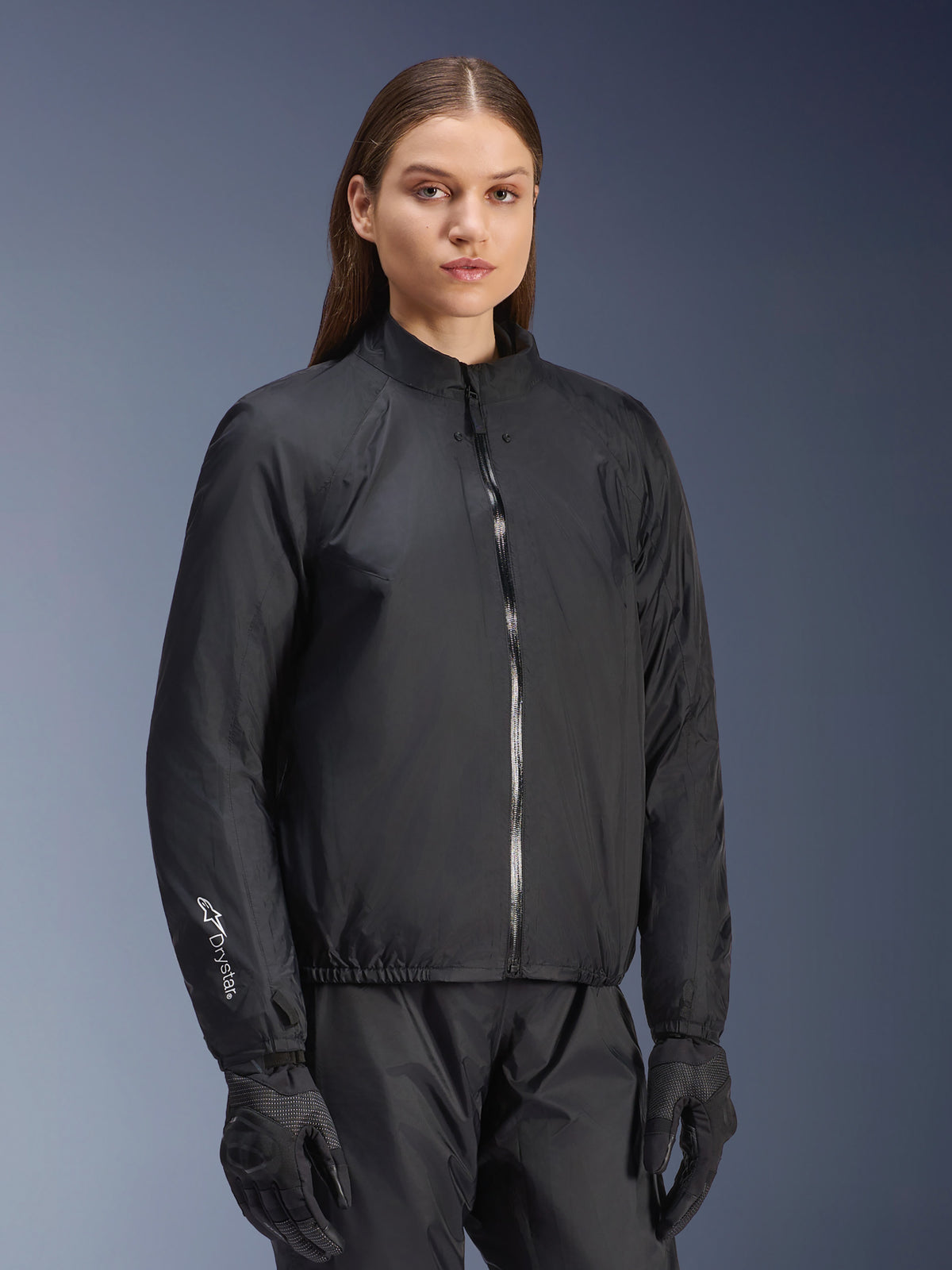 Veste Alpinestars Stella Andes Air Drystar®, veste de moto pour femme, noire, présentant la membrane imperméable amovible avec fermeture éclair intégrale et logo Drystar sur la manche, portée avec un pantalon et des gants de moto noirs assortis