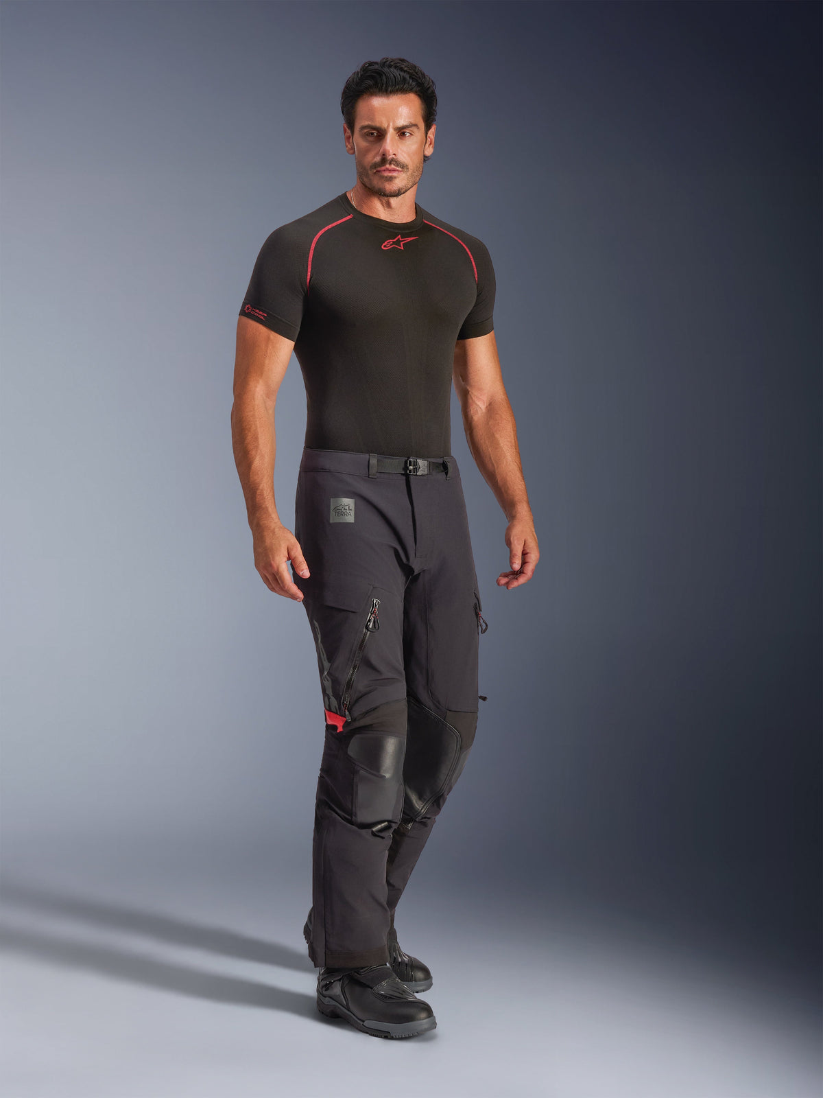 Alpinestars Halo Pro Drystar® XF Laminierte Hose, Black Dark Shadow, Adventure-Motorradhose getragen mit schwarzem Base-Layer und Stiefeln, mit großen Belüftungsöffnungen am Oberschenkel, Knieverstärkungen aus Leder und einem Gürtel mit Magnetschnalle, entwickelt für All-Terrain-Performance.