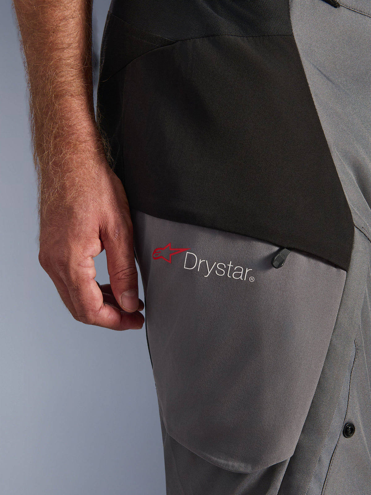 Alpinestars Andes V4 Drystar® broek, zwart donkergrijs, close-up van het dijdetail met rood sterlogo en Drystar®-branding, duurzame textielconstructie met ritszak, adventure motorkleding