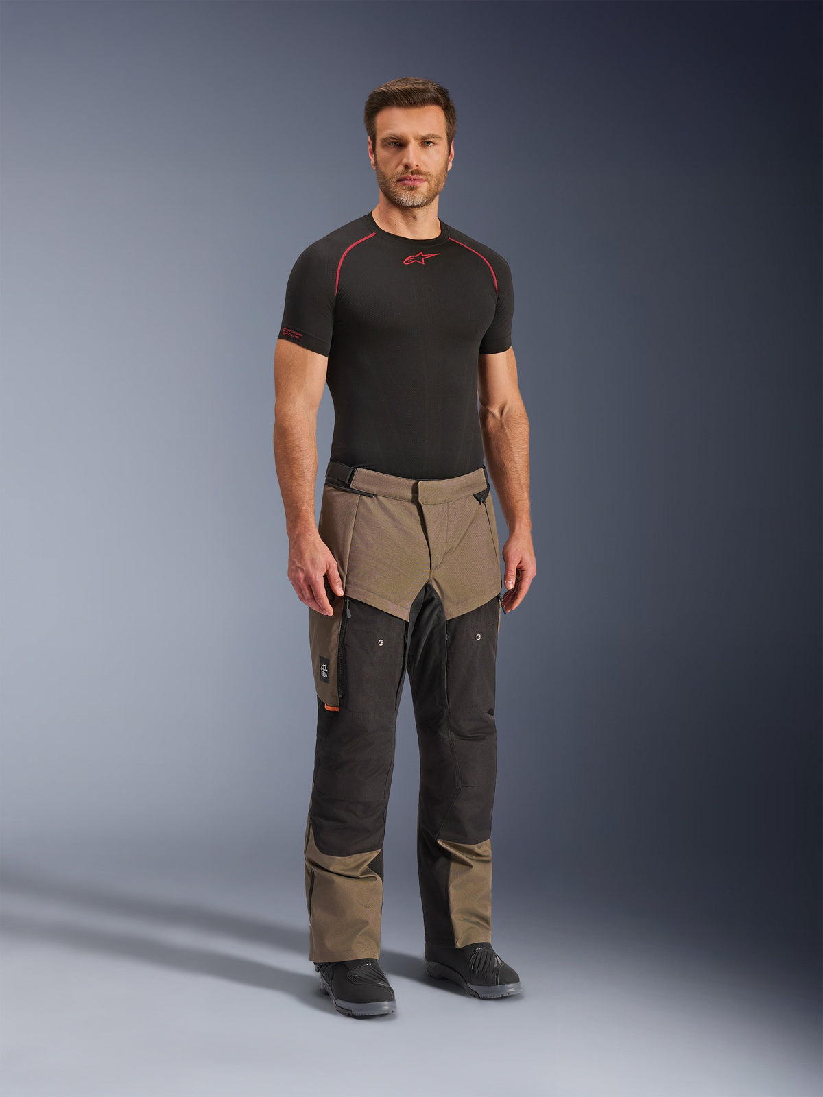 Alpinestars Cusco Drystar® Pants, Adventure Motorcycle Pants, Walnut and Black, worn by a model with a black base layer and boots, featuring large thigh cargo pockets, ventilation zippers, and a rugged dual-tone design.
