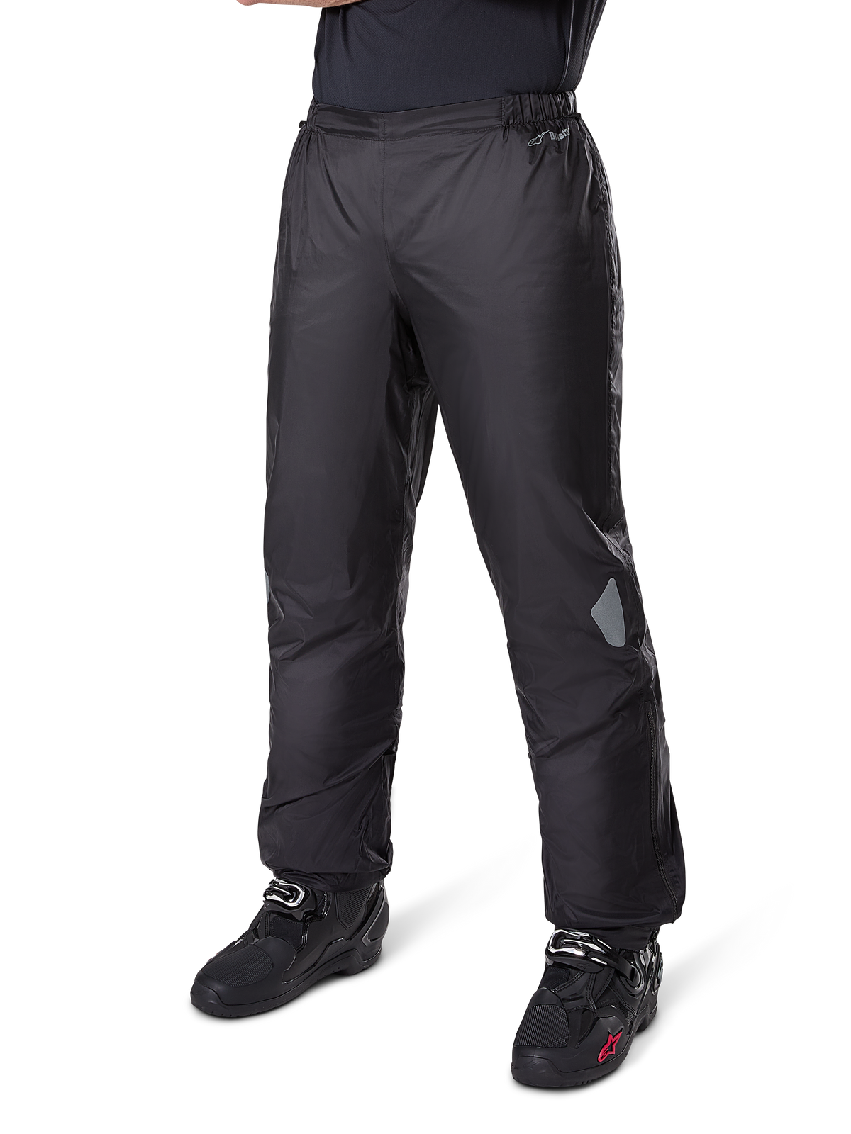Alpinestars Bogotá Pro Drystar® 3-Jahreszeiten-Hose, Adventure-Touring-Motorradhose, Schwarz, getragen mit schwarzen Motorradstiefeln, mit reflektierenden Einsätzen an den Knien und Drystar-Logo, leichtes wasserdichtes Textildesign für das Fahren zu jeder Jahreszeit.