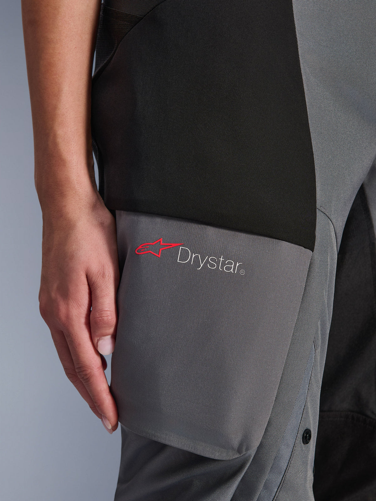 Pantalon Alpinestars Stella Andes V4 Drystar®, pantalon de moto adventure-touring pour femme, noir et gris foncé, détail de la cuisse montrant le logo Drystar et l'étoile rouge Alpinestars sur des panneaux textiles renforcés