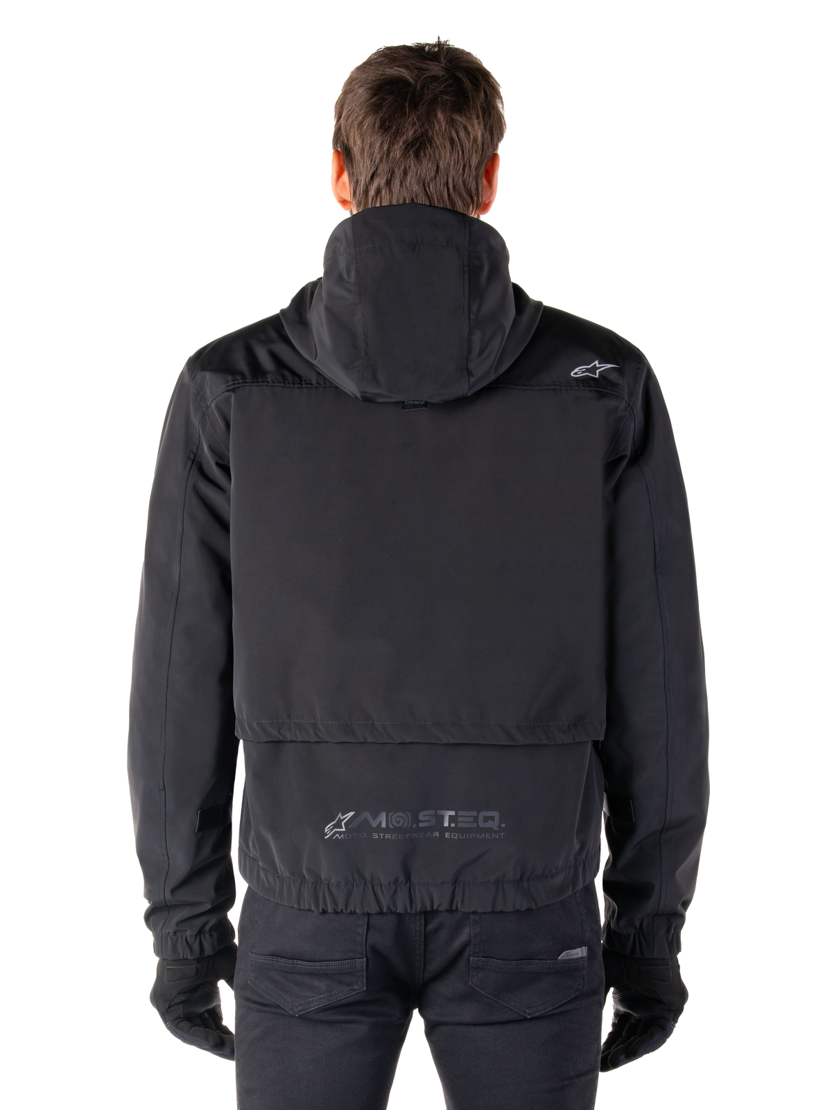 Alpinestars Mootant Wasserdichter Parka, schwarze Motorradjacke, Rückansicht mit Kapuzendesign, kleines Astar-Logo auf der Schulter und reflektierendes MO.ST.EQ. Branding am unteren Rücken