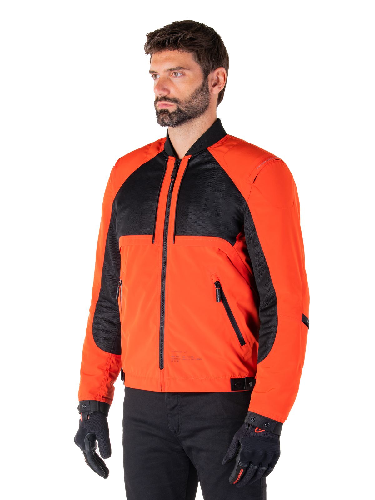 Alpinestars Mootant Waterproof Parka in Spicy Orange en zwart, modulaire motorjas getoond in bomber-configuratie, voorzien van zwart mesh en oranje textielpanelen, urban contemporary motorkleding gedragen met zwarte handschoenen