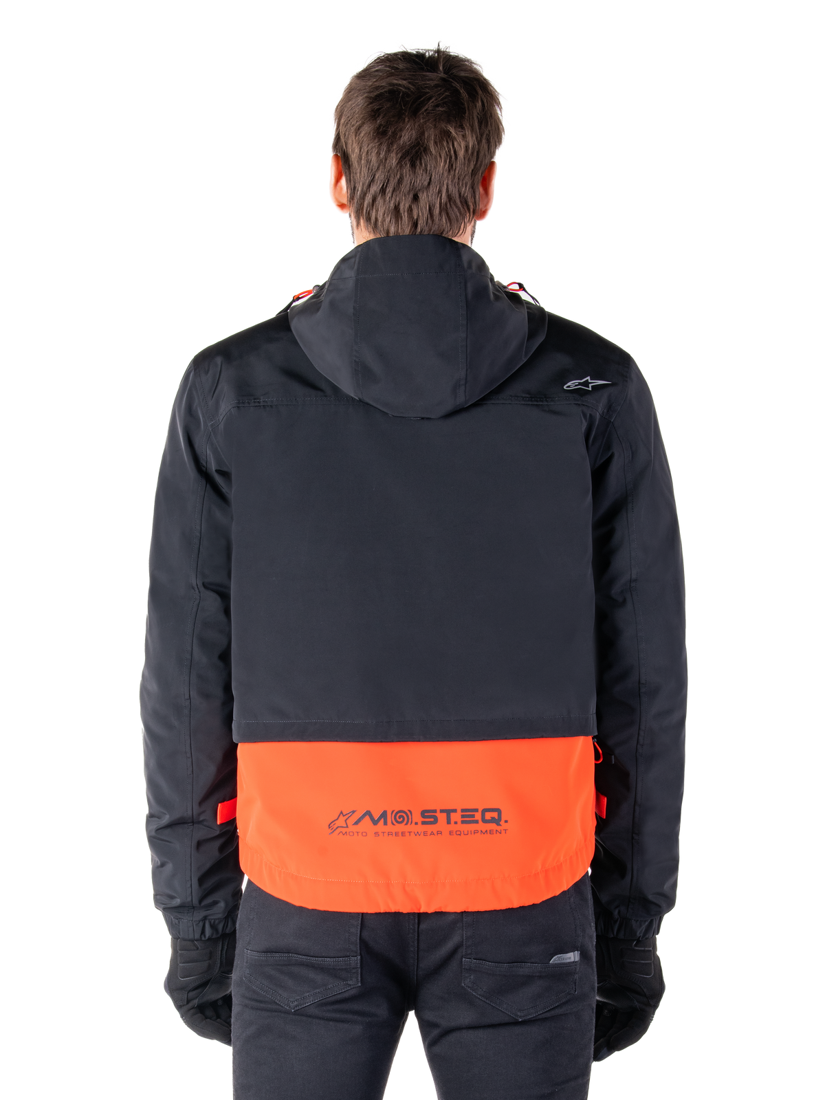 Alpinestars Mootant Waterproof Parka in Spicy Orange en zwart, achteraanzicht met zwart bovendeel met capuchon en oranje onderpaneel voorzien van het MO.ST.EQ. woordmerk, functionele motor-streetwear.
