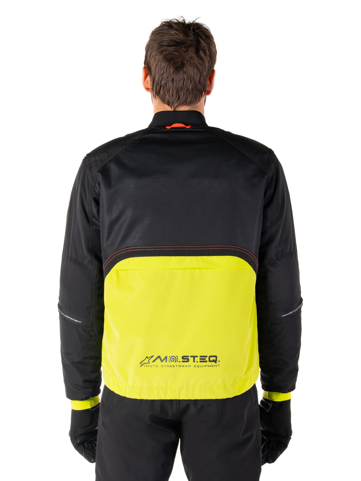 Alpinestars Mootant Waterproof Parka, Motorradjacke, Lime Punch und Schwarz, Rückansicht mit schwarzem Mesh-Oberteil für Belüftung und limettengrünem unterem Bereich mit MO.ST.EQ. Logo, getragen mit schwarzer Hose und Handschuhen