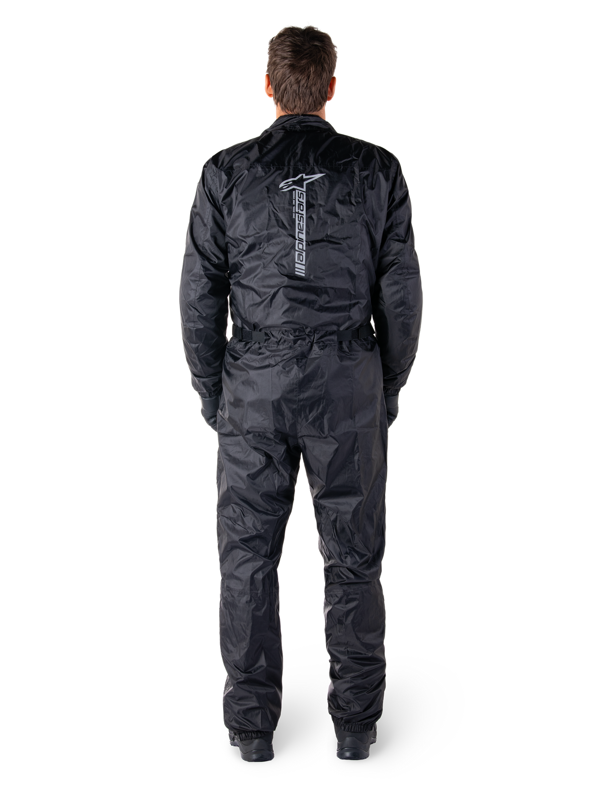 Alpinestars Hurricane Rain V2 Suit, Black One-Piece Waterproof Motorcycle Suit, back view showing large vertical Alpinestars wordmark and logo, lightweight crinkled fabric with elasticated waist and cuffs, designed for wet weather riding protection.