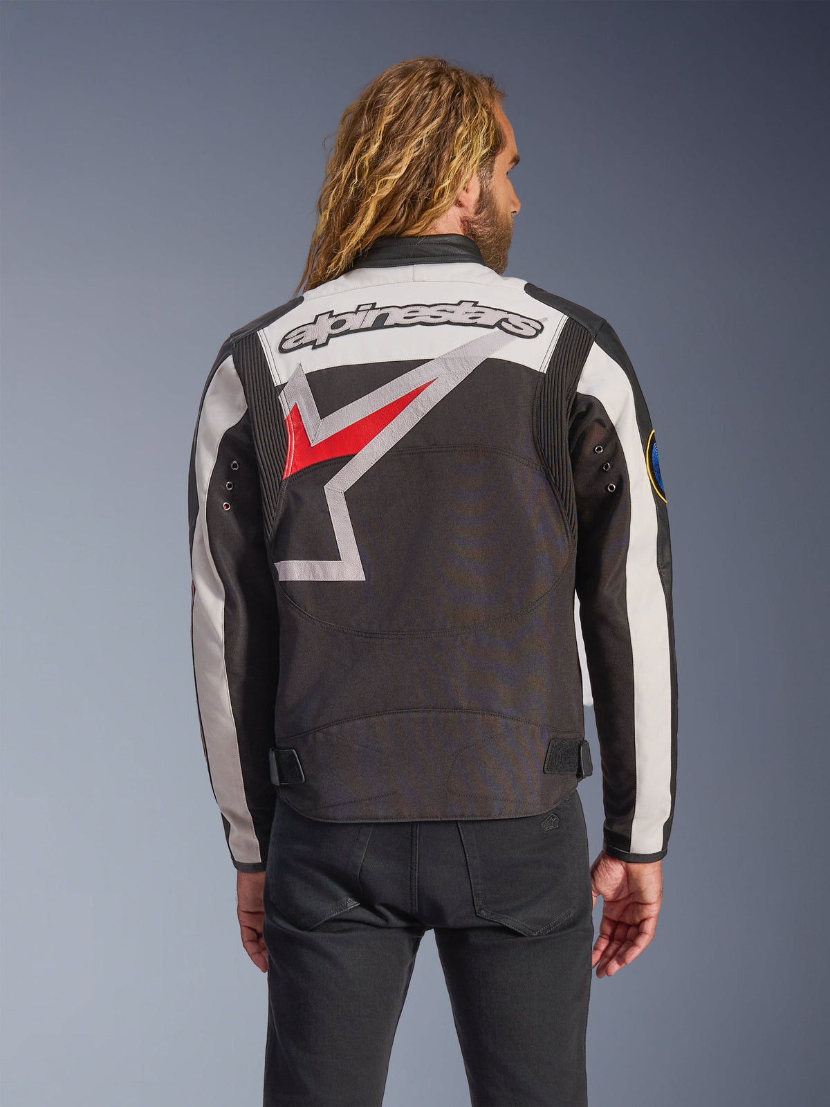 Veste Alpinestars Axton, veste de moto, noir, blanc cassé et rouge vif, vue arrière présentant un grand logo étoile enveloppant et un mot-symbole, design d'inspiration racing vintage avec panneaux accordéon aux épaules et ajusteurs à la taille