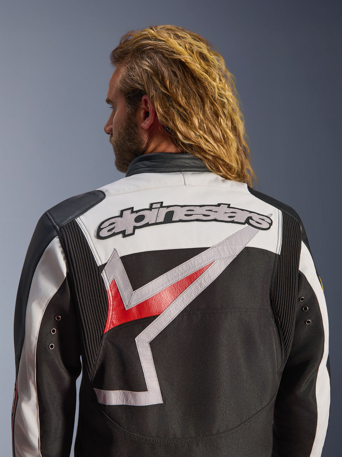 Veste Alpinestars Axton, veste de moto, noir, blanc cassé et rouge vif, vue arrière avec grand logo Alpinestars brodé et graphique stylisé, panneaux en accordéon aux épaules pour la mobilité, design d'inspiration vintage avec détails d'œillets métalliques