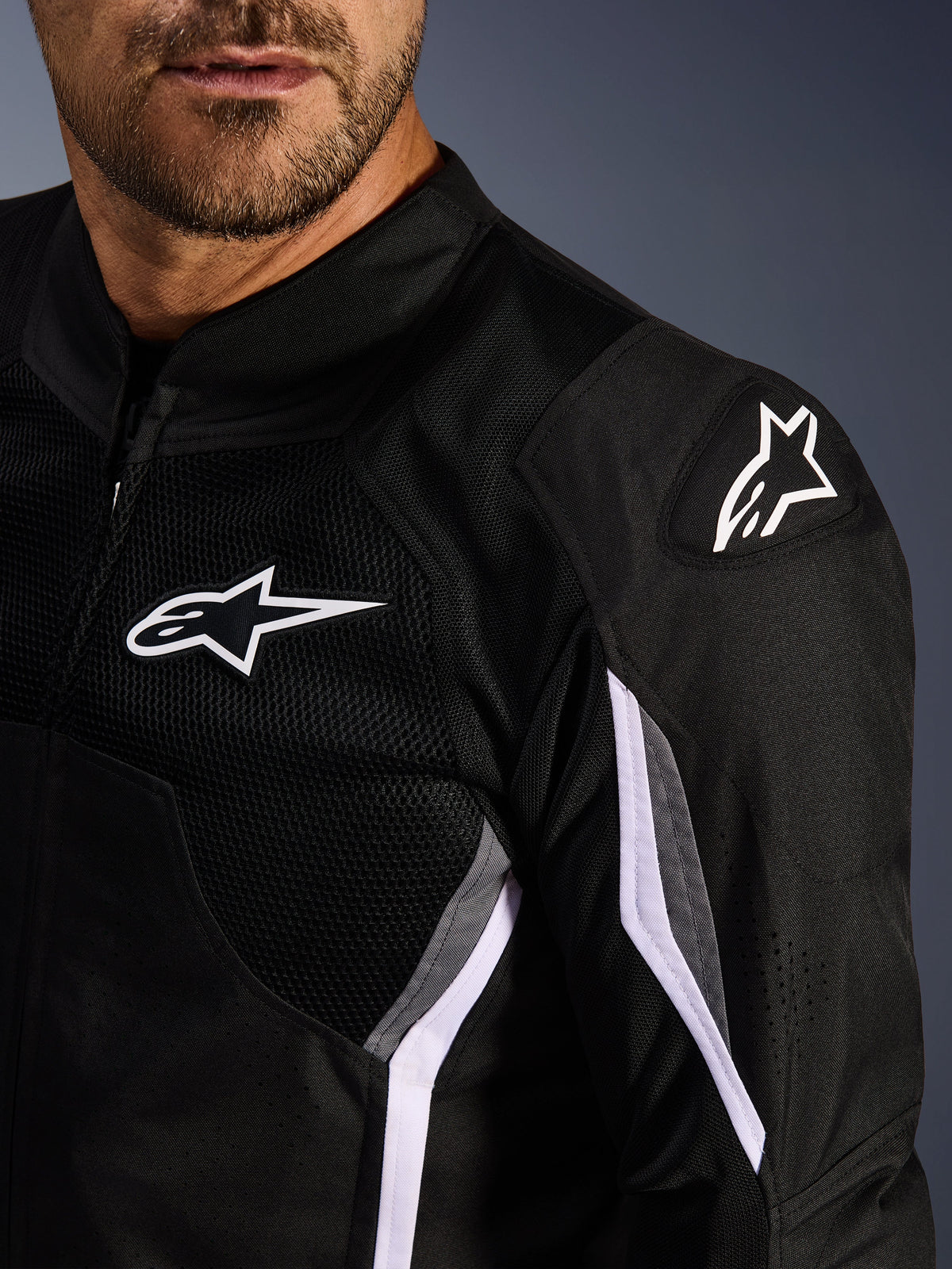 Alpinestars AST V3 Air Jacket, textiel motorjas, zwart donkergrijs wit, close-up met mesh-panelen, wit Alpinestars-logo op de borst en schouder en DFS GP Lite Evo externe schouderschuivers