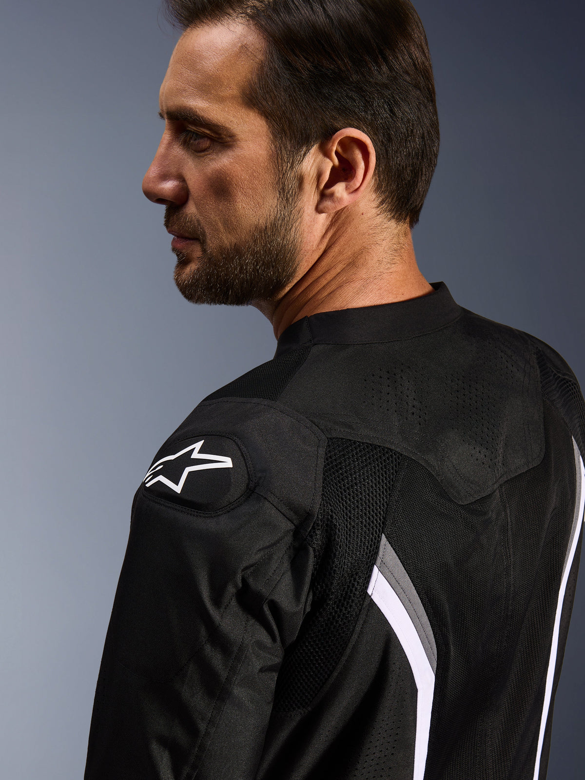 Alpinestars AST V3 Air Jacket, motorjas, zwart donkergrijs en wit, close-up van de achterzijde met wit sterlogo op de schouder en laser-geperforeerde mesh-panelen voor ventilatie.