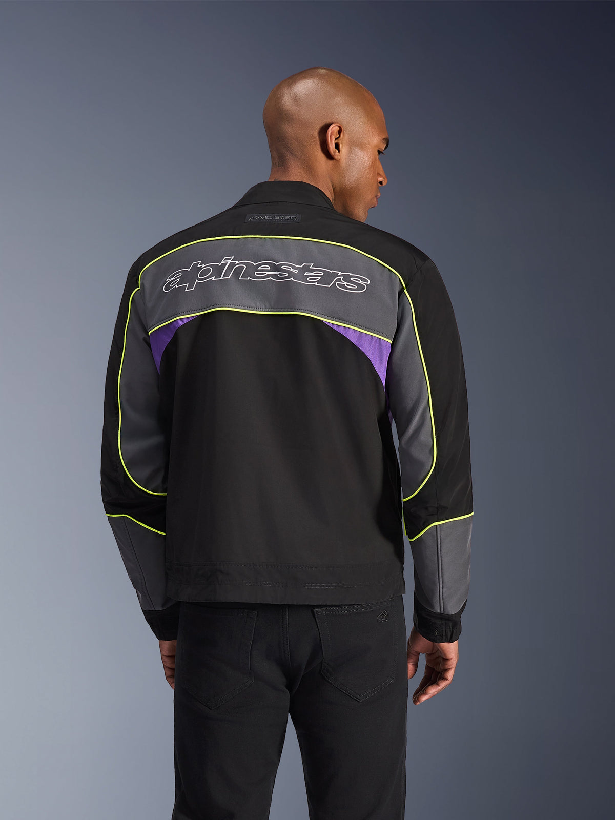 Veste Alpinestars Unite, veste de moto urbaine, Black Asphalt Violet, vue de dos avec empiècements gris et accents violets, liserés jaune citron, grand lettrage Alpinestars sur le haut du dos, design streetwear minimaliste