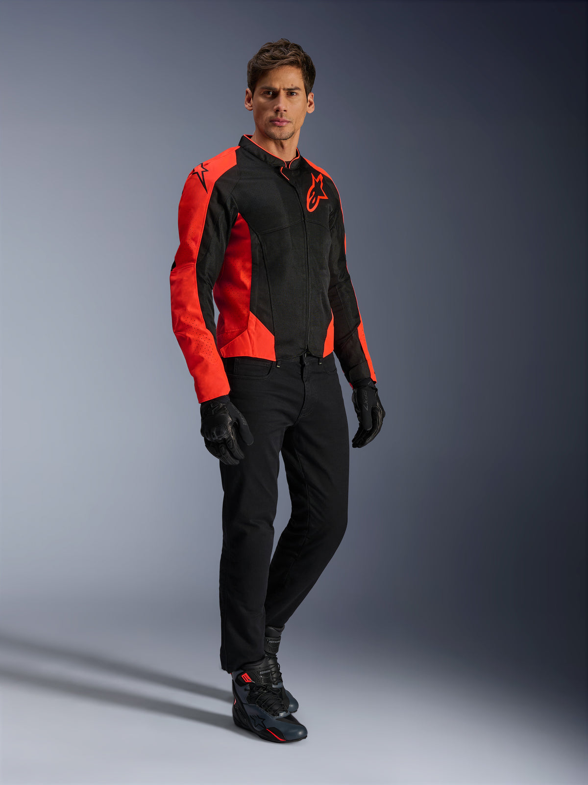 Alpinestars Viper Air V4 Jacke, Motorradjacke, Rot Fluo und Schwarz, getragen von einem Modell mit schwarzen Motorradjeans, schwarzen Handschuhen und Motorradschuhen, Textil-Mesh-Design mit markanten roten Einsätzen und Stern-Logo, sportliche Straßenbekleidung